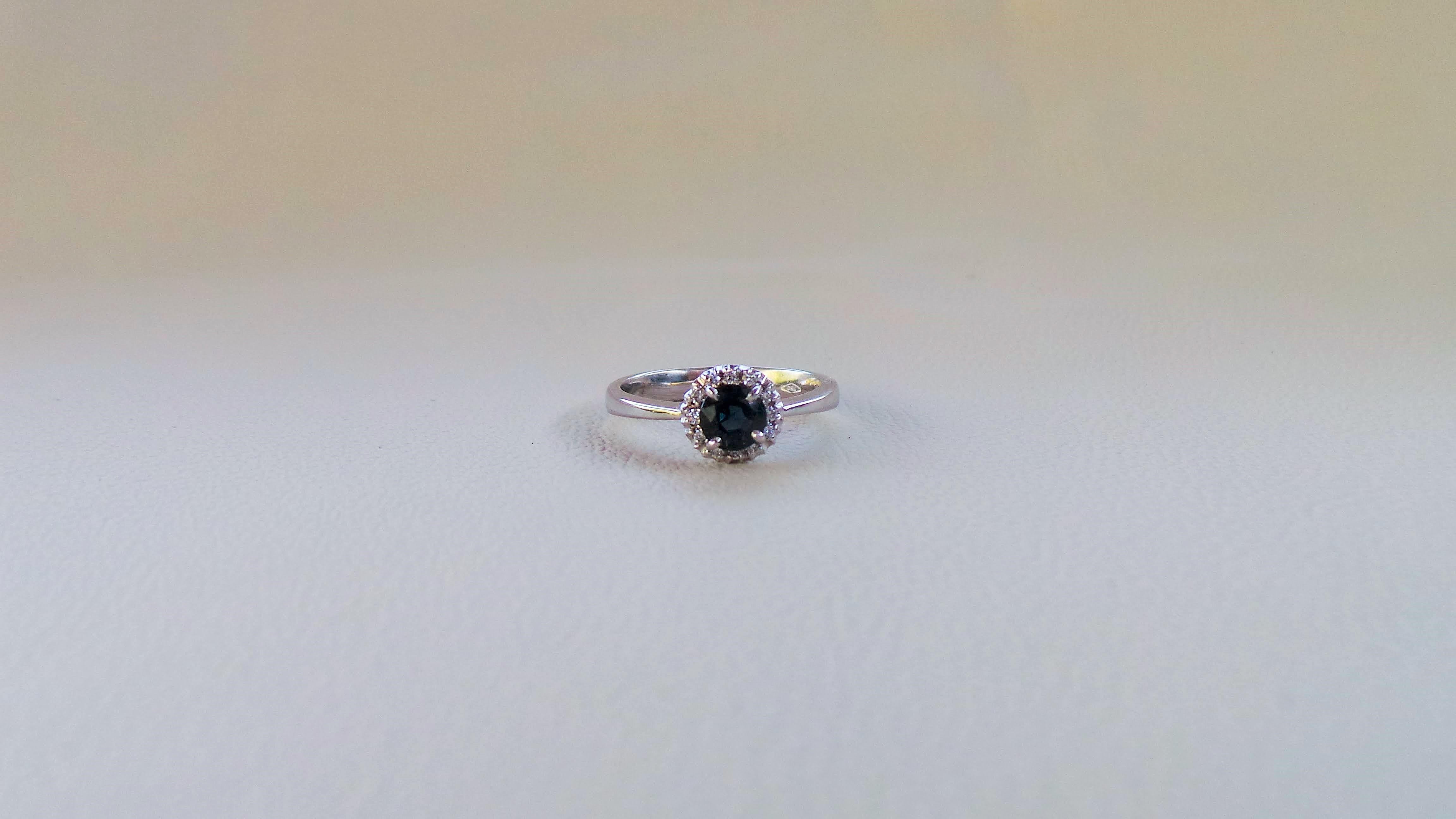 Andrea Macinai entwirft eine eigene Kollektion für Verlobungsringe  mit einem wunderschönen runden dunkelblauen Saphir und Diamanten.
Der Ring wurde nach der natürlichen Linie des Steins entworfen und gefertigt.
0.6 Karat runder blauer Saphir,