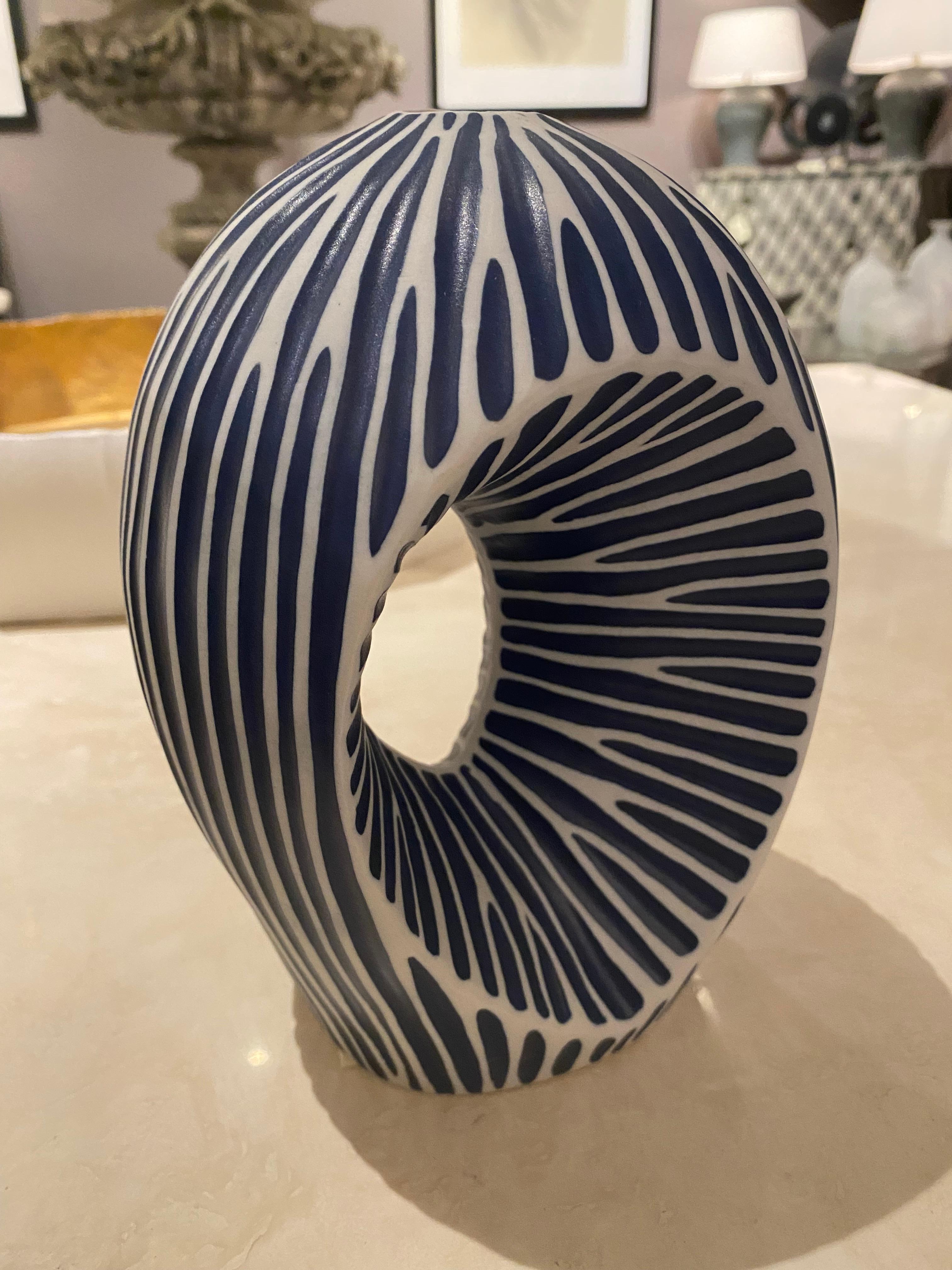 Contemporary Thailand dark blue with thin white stripe ceramic vase.
Indented hole design in the middle of the vase.
Can hold water.
Part of a very large collection of blue and white vases in various shapes and sizes.