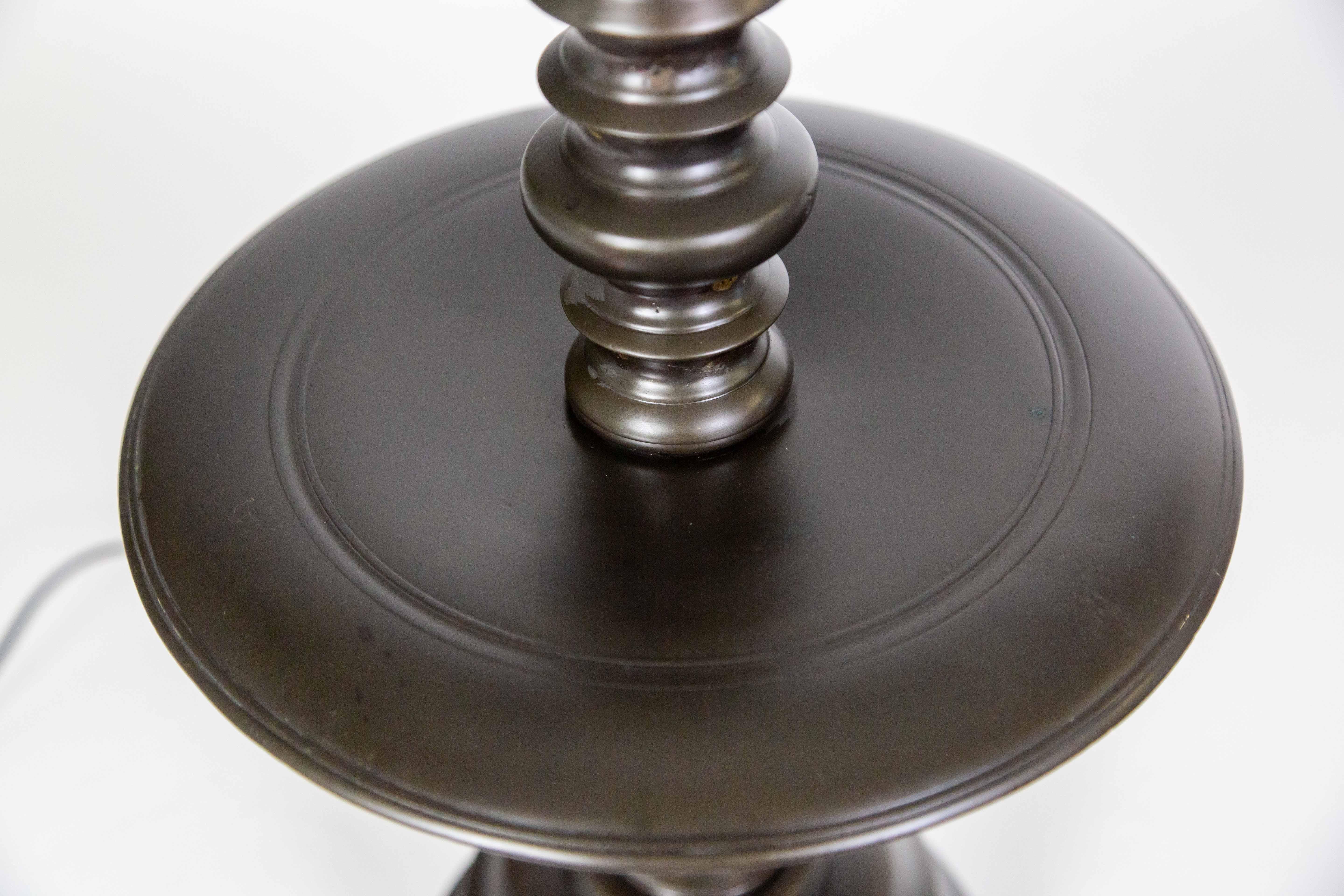 A Dutch Colonial lamp with a dish in the center of the turned-style, cast bronze body. It has a rich, dark, oil-rubbed bronze patina, a large base, and balanced proportions. The center try can remain bare, but is large enough to be used to place