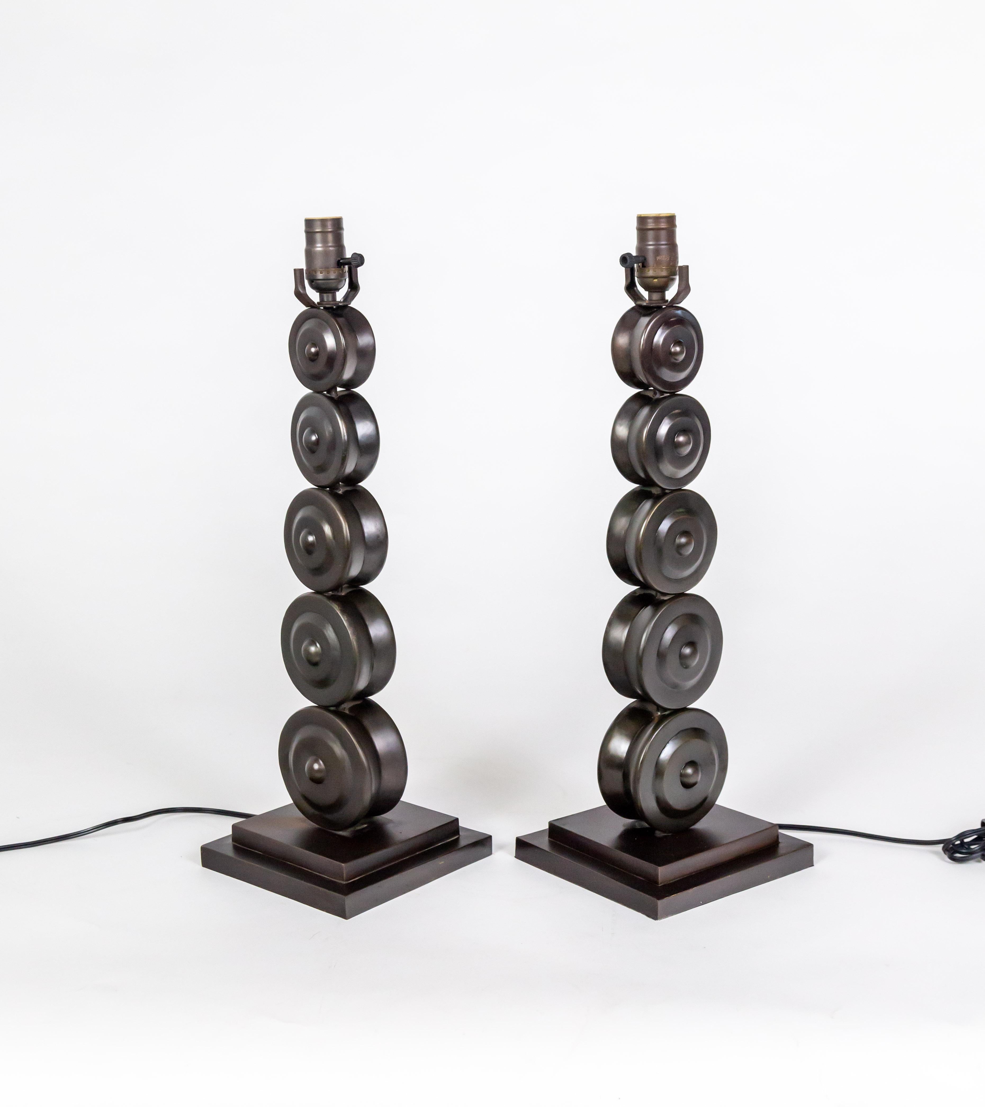 A pair of brass table lamps with an oil-rubbed bronze patina in the form of stacked wheel shapes, tapering slightly in size, sitting on square bases. This sculptural design looks great in traditional, modern, and contemporary interiors. Newly wired.