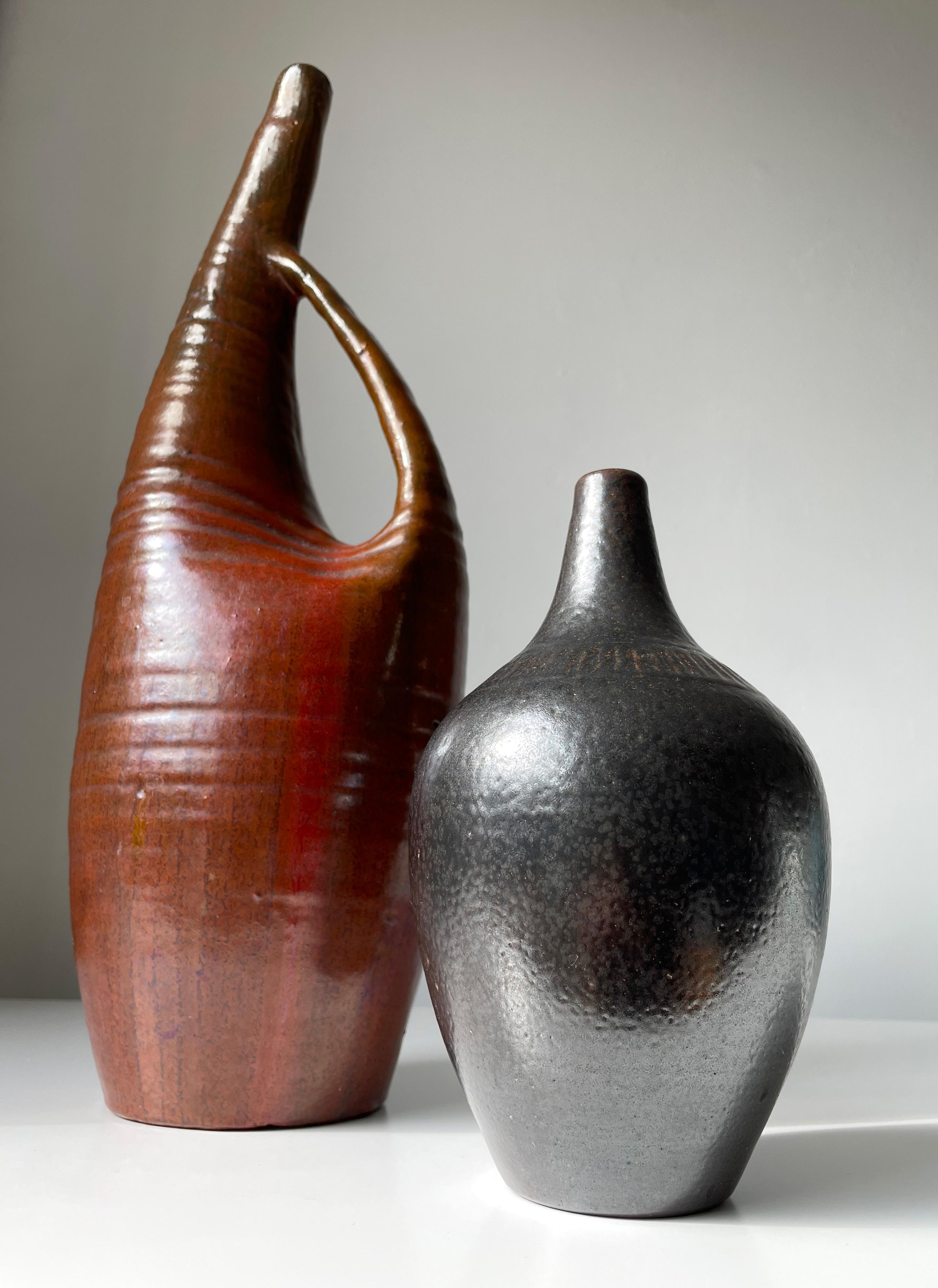 Muted blackish dark brown glazed stoneware vase with precise and narrow vertically incised lined pattern band around the top of the belly. Soft rounded bottle shape with slender neck and narrow base. Inscribed under base. Designed by ceramic artist