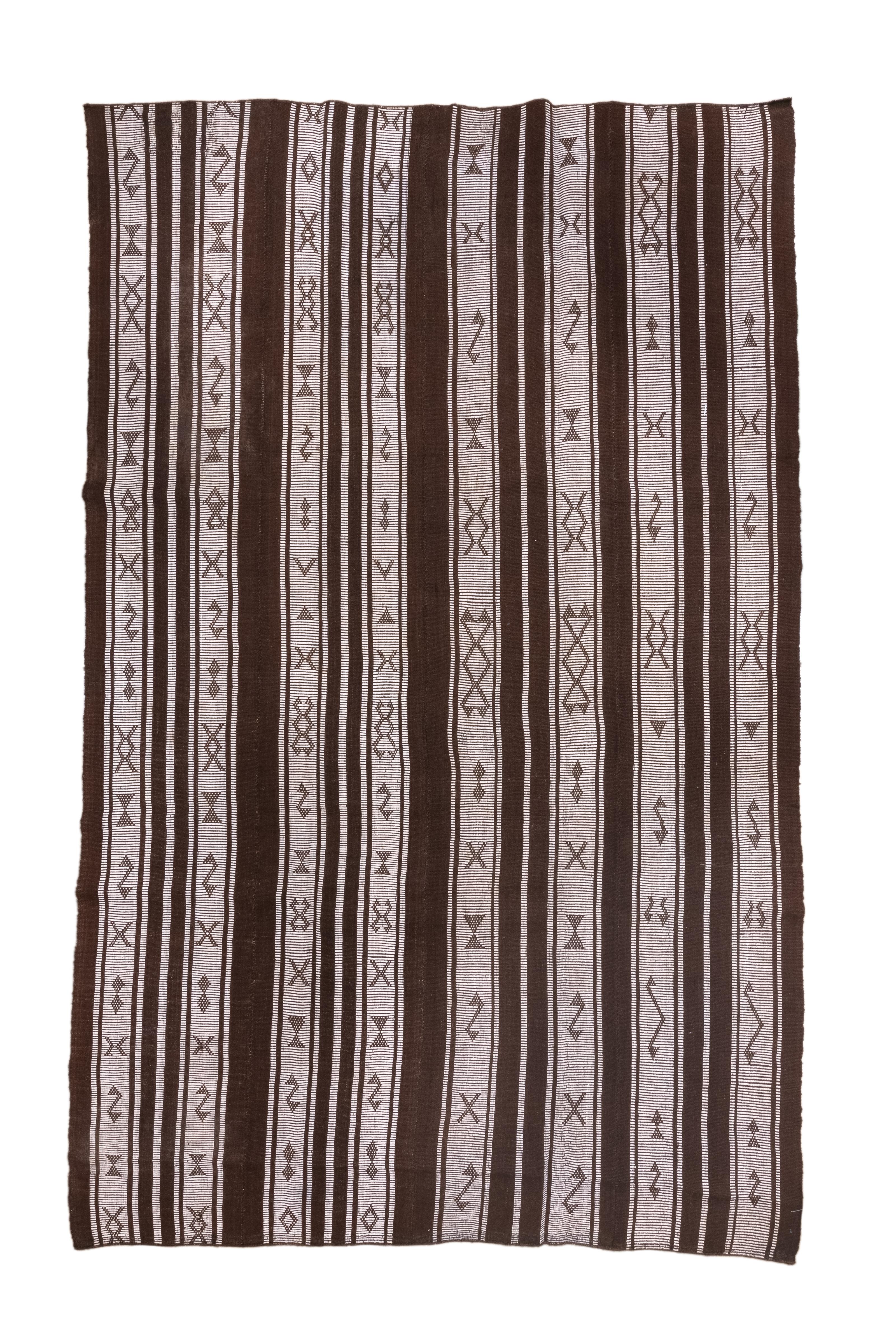 Here the warp faced constituent bands run vertically in shades of dark brown wool and off-white. cotton. The brown bands are plain while the ivory bands have lozenges, S’s, X’s or related devices. Adjustable dimensions. The assemblage is recent