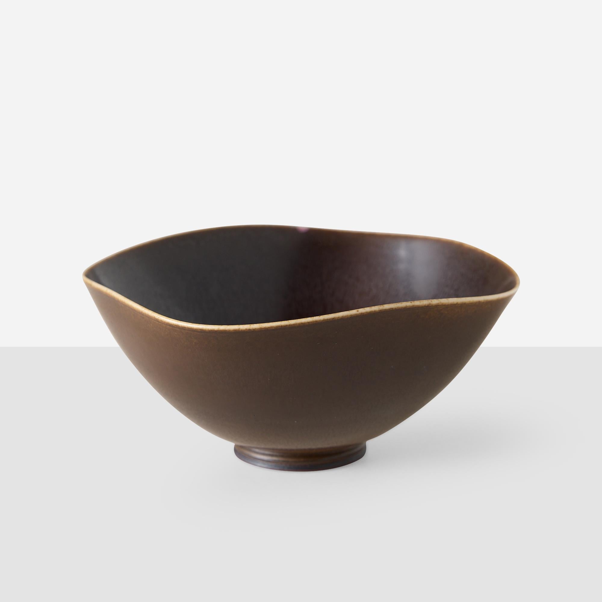 Cuenco de cerámica marrón oscuro de Berndt Friberg, fabricado en la fábrica de porcelana Gustavsberg de Suecia. El cuenco presenta un borde pálido y una forma irregular y asimétrica con una superficie finamente texturada característica de la obra de