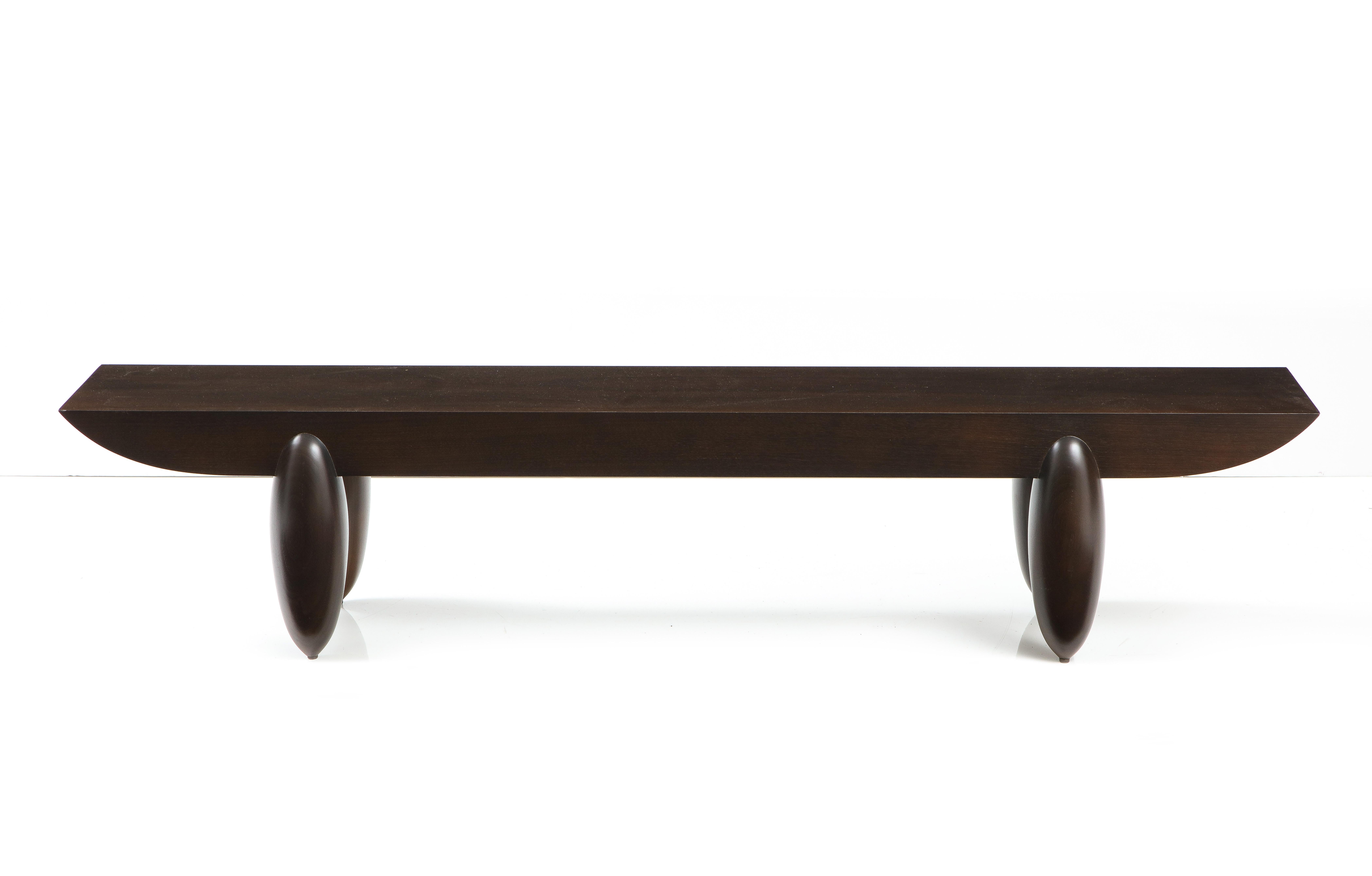 A dark chocolate brown wood bench by Christian Liaigre, the elegant and simple top with tapered edges resting on four bulbous legs, made in France for Holly Hunt stamped underneath. Simple, big, bold and beautiful, this bench is compatible with a