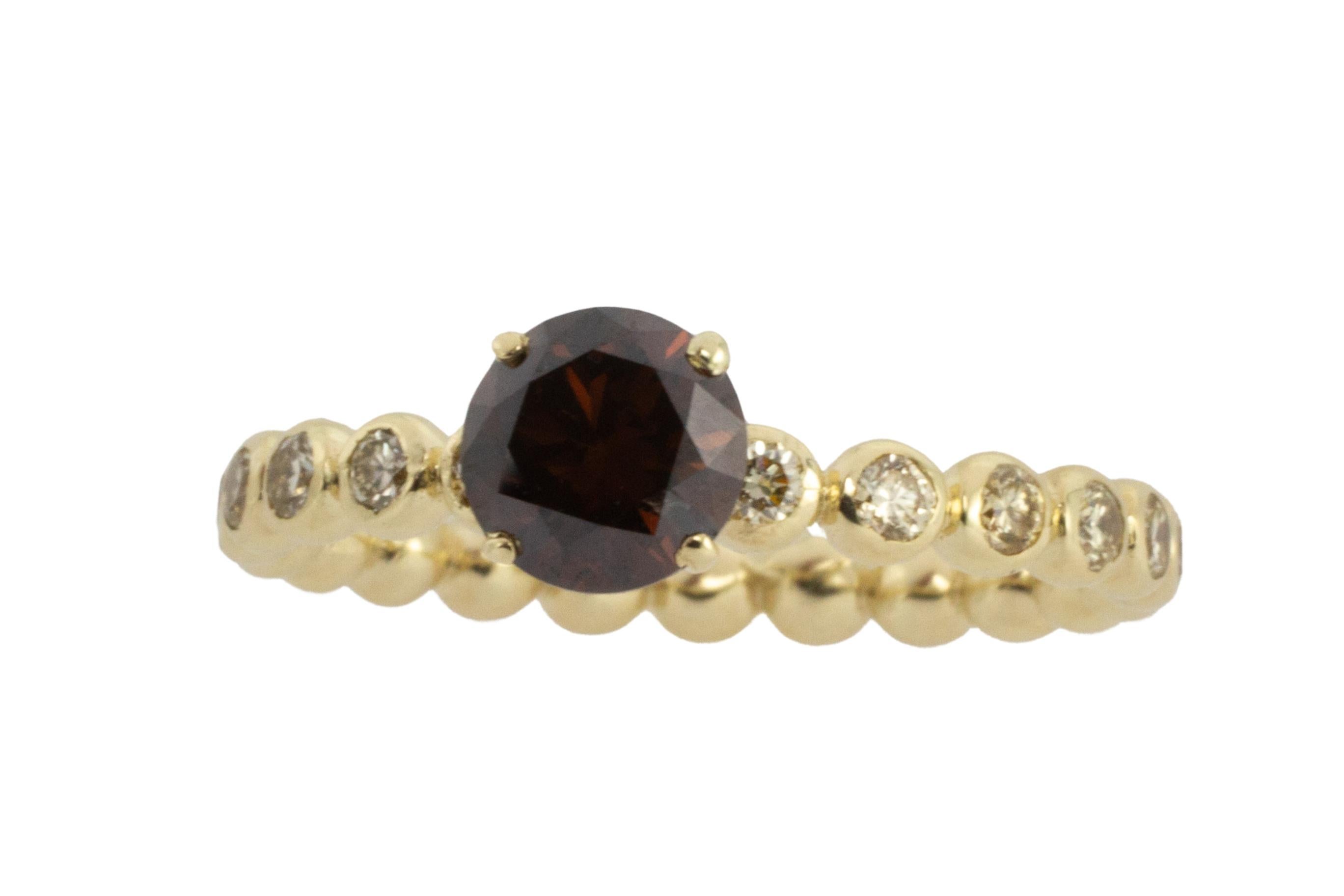A 14 carat gold ring set with a dark brown diamond and 22 brilliant cut diamonds in the band. 

The natural fancy dark orangy brown diamond is a .90 carat stone and is VS1 in quality, the diamond sits in an elegant four prong setting. 

The 22
