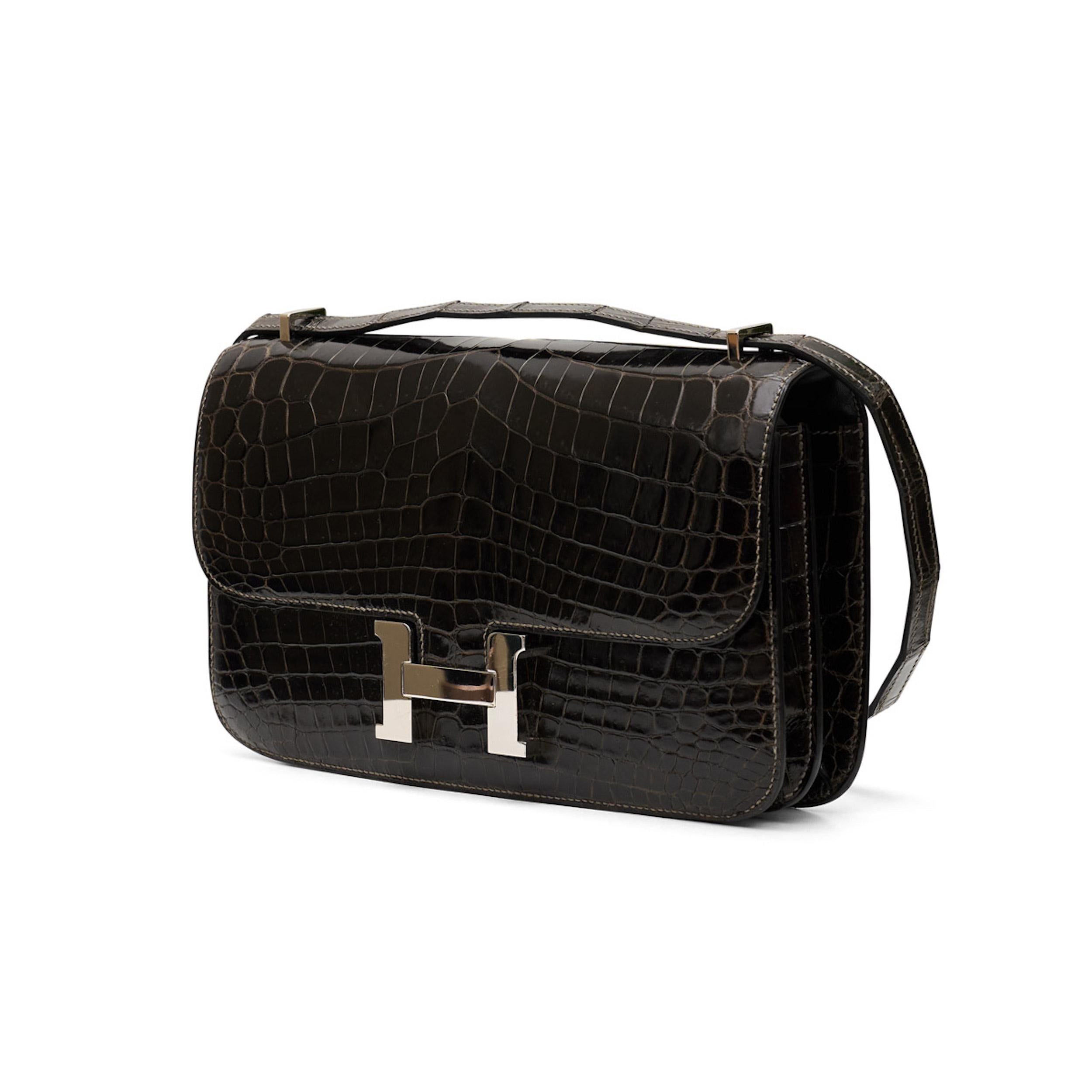 This 25cm Constance Elan shoulder bag from Hermès was meticulously crafted in France from highly precious exotic leather in dark chocolate. Offset with silver-tone palladium-plated hardware, its slender body is adorned with the brand's signature 