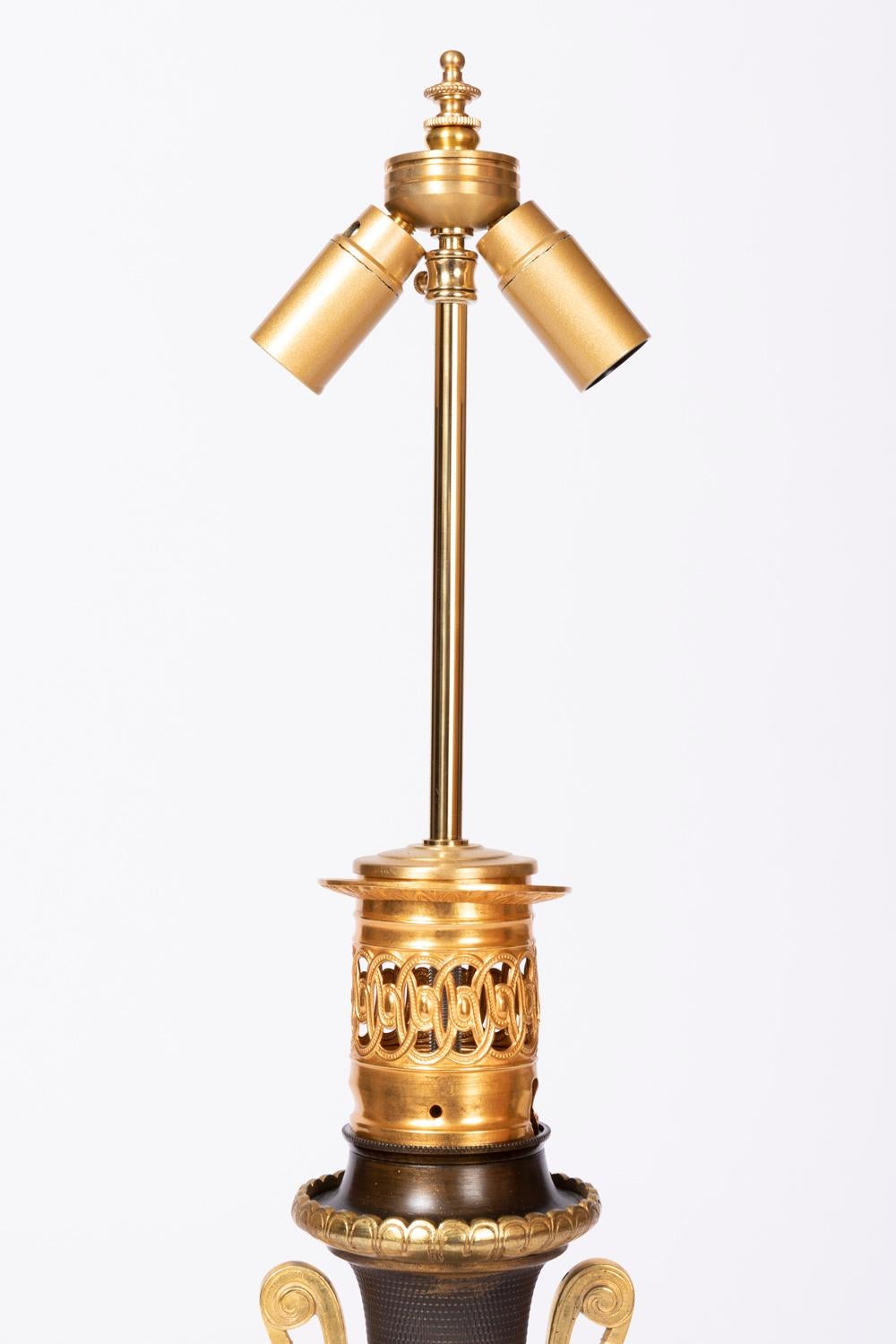 Baluster shape lamp in brown guilloche sheet metal with a second bulged part beneath the body.
Chiselled and gilt bronze mount. High part with openwork interlacing motifs and a frieze of gadroons. Ringed neck where are fixed neoclassical handles