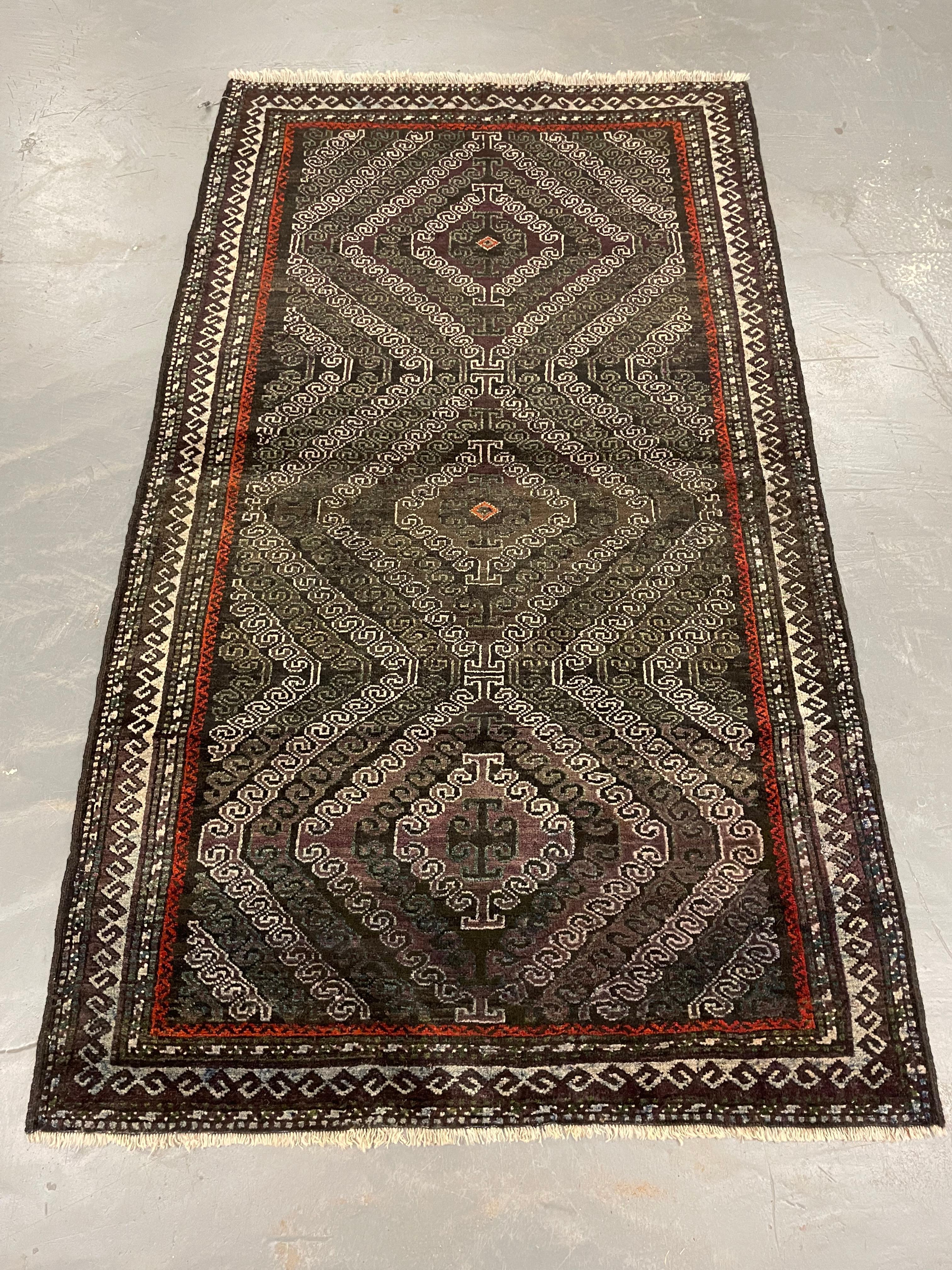 Dieser traditionelle Balouch-Teppich wurde in den 1930er Jahren von Hand gewebt. Das Hauptdesign besteht aus drei großen Medaillons mit Zig Zag-Mustern, gewebt in tiefem Braun auf schwarzem und elfenbeinfarbenem Hintergrund mit einem Hauch von