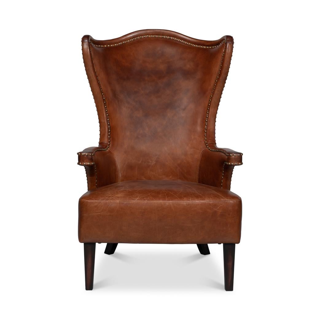 Upholstered in rich, full-grain Newark brown leather, this chair features a dramatic high-back design that creates an elegant silhouette. The winged sides and gently curved arms are accentuated with meticulous nailhead trim, adding a refined touch