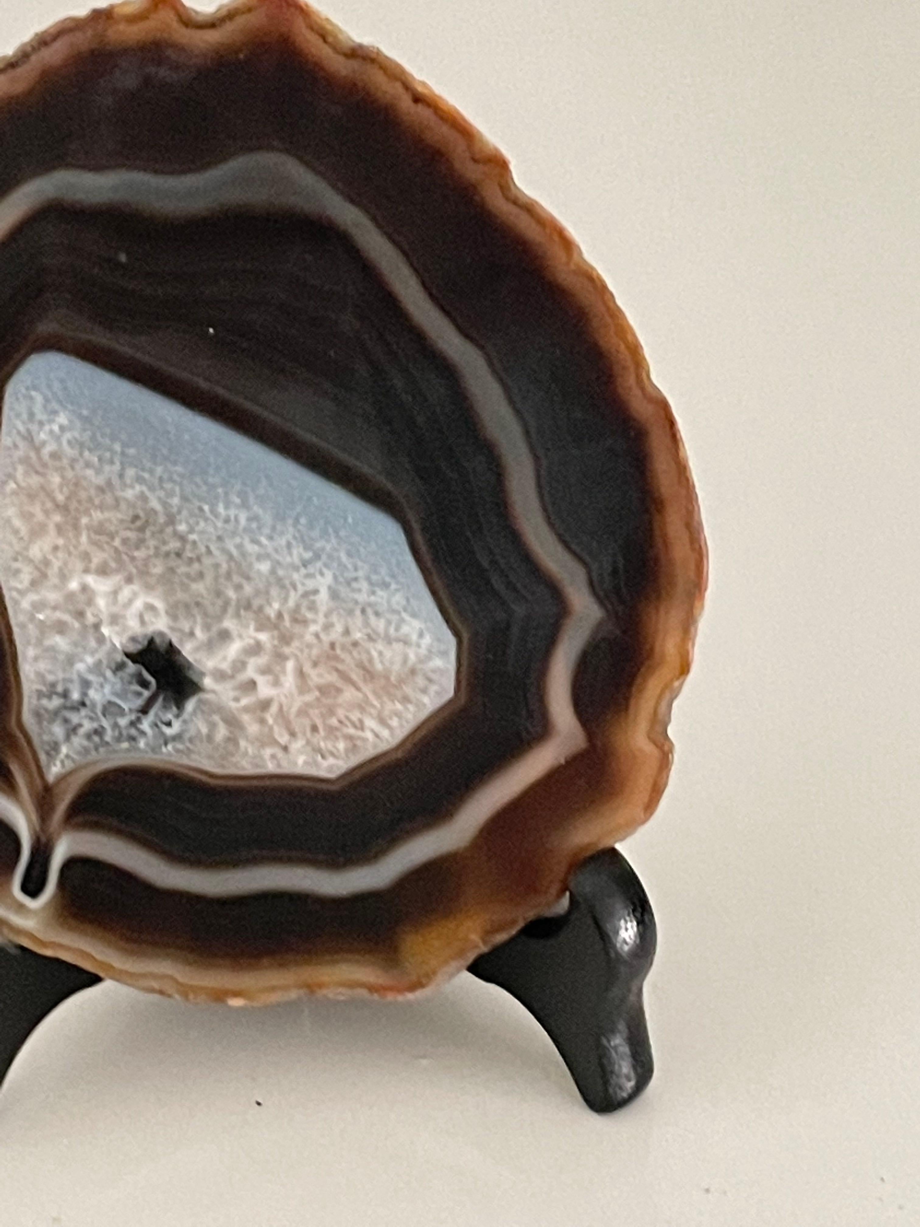Brazilian thin slice of agate mounted on a wooden stand.
Agate is a banded form of finely-grained, microcrystalline Quartz. 
The lovely brown color patterns and cream banding make this translucent gemstone very unique. 
Agates can have many