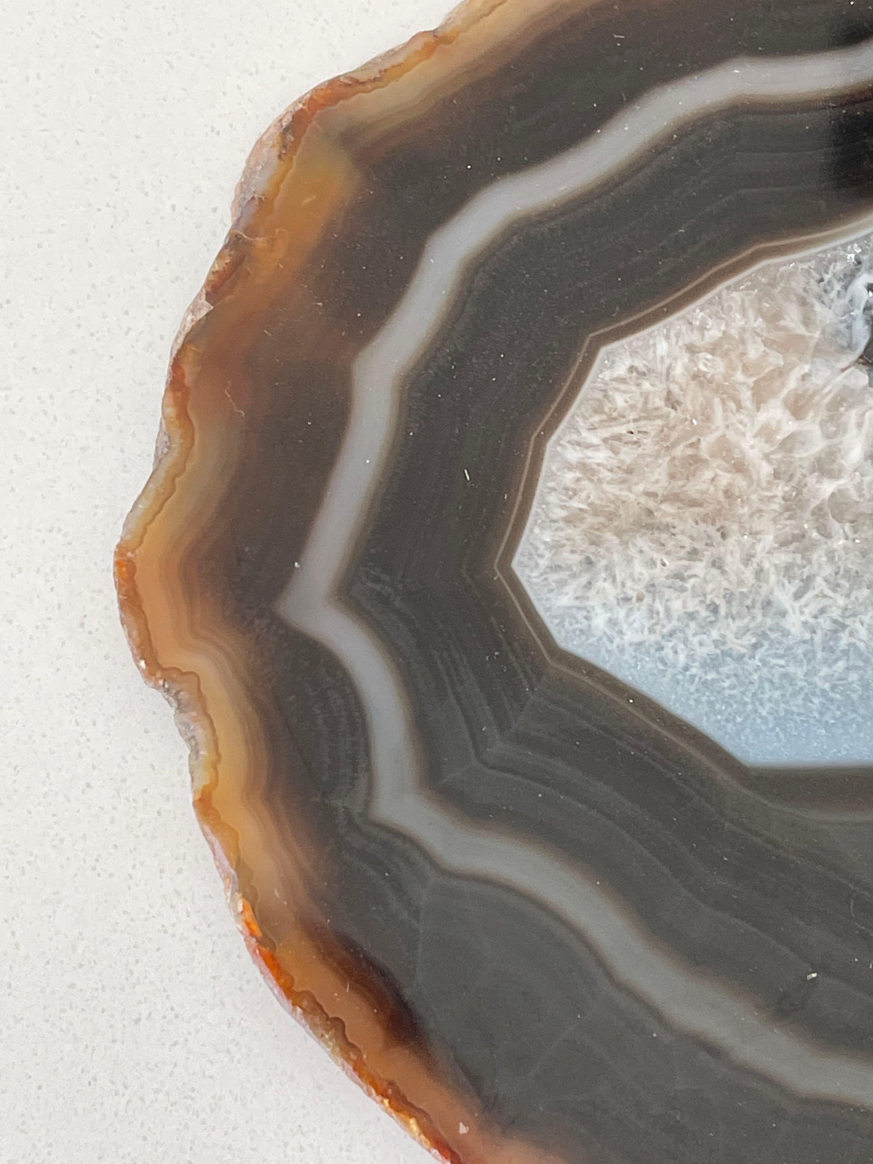 Sottile fetta di agata brasiliana montata su un supporto di legno.
L'agata è una forma a bande di quarzo microcristallino a grana fine. 
Gli incantevoli motivi di colore marrone e le bande color crema rendono questa gemma traslucida davvero unica.