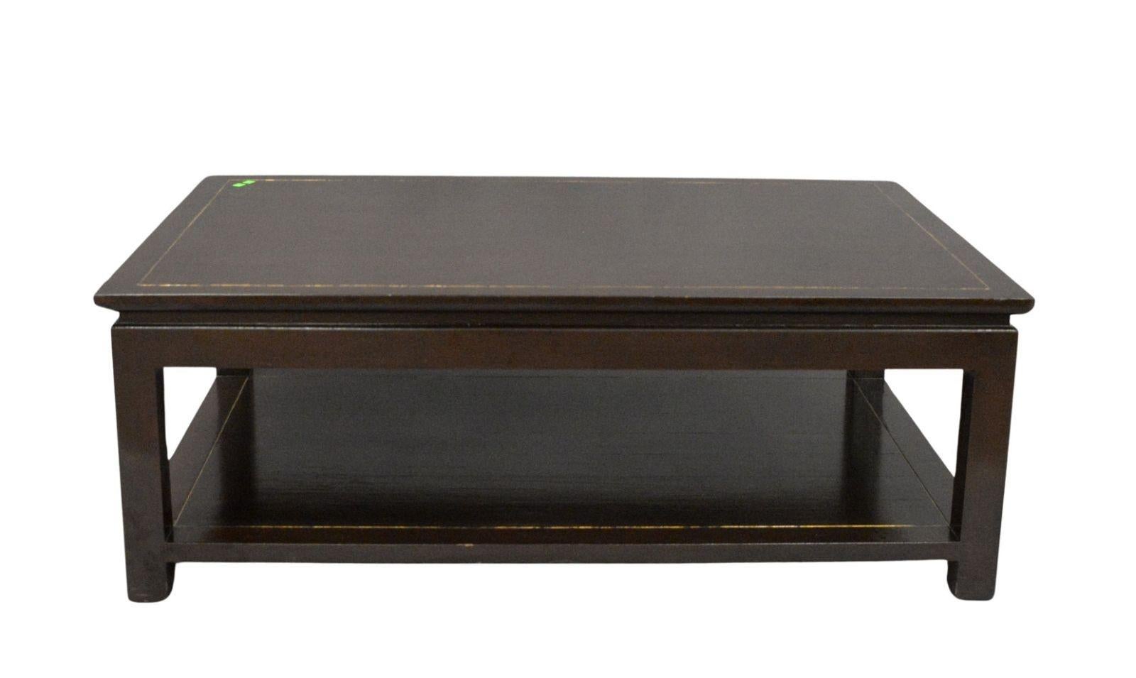 A dark chocolate two tier coffee table with gilt detail creating a two inch border for both the top and lower shelf.  The polished finish creates an elegant feel for the table, useful in multiple style rooms.