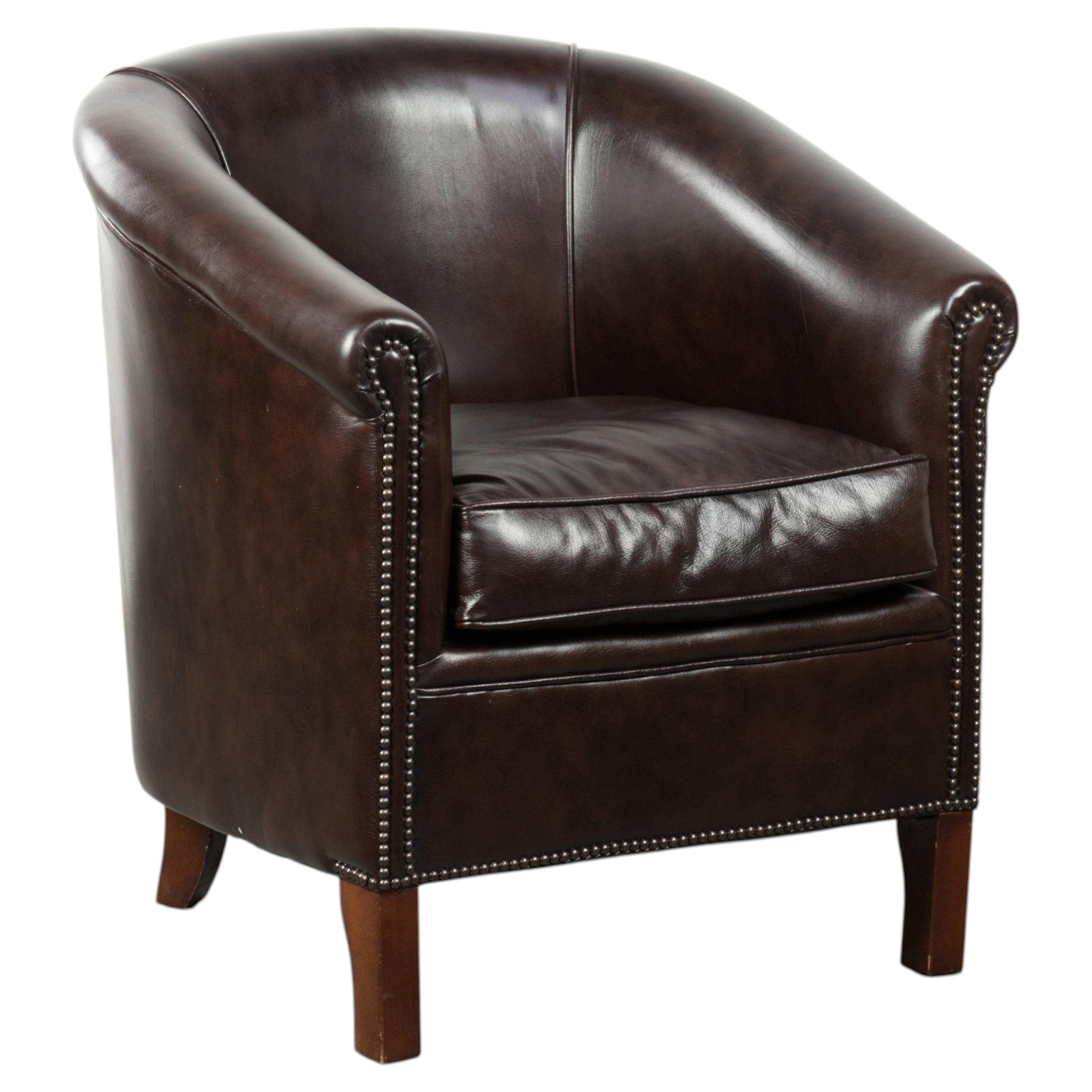 Fauteuil club en cuir de vachette foncé en bon état avec un design anglais.