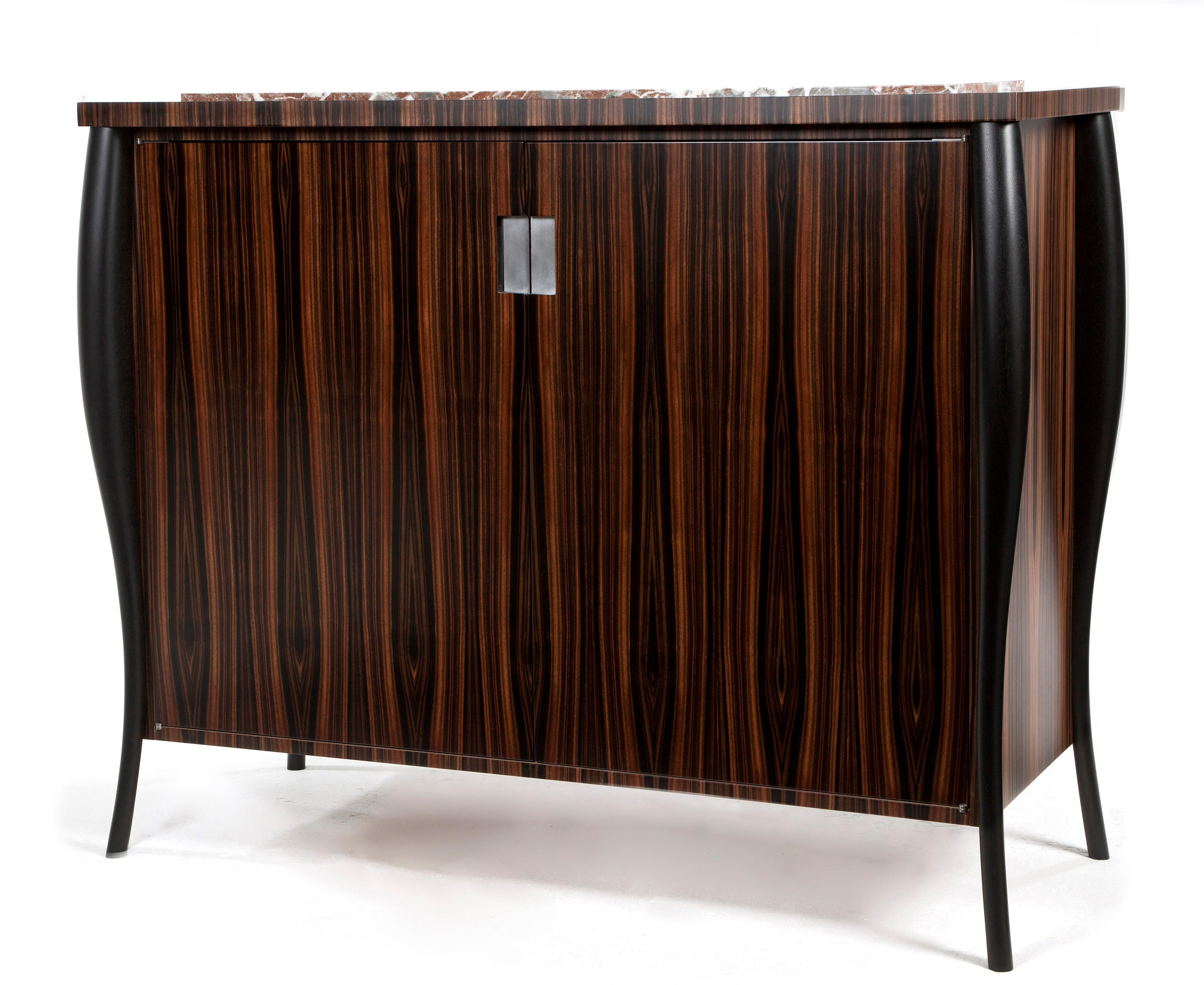 Book-matched Macassar ebony drinks cabinet. 
The hand-sculpted legs in ebonised walnut and waterfall veneer edging encase a beautiful Irish stone top. 

The interior of the cabinet is made from ripple sycamore and the inset handles are finished with