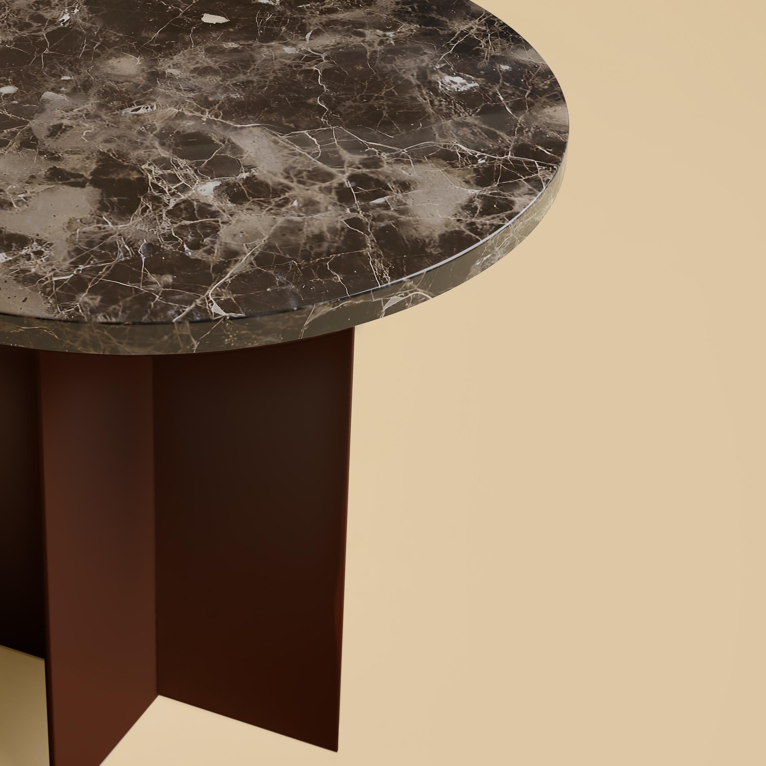 La table basse Baker est fabriquée avec une base en métal revêtu de poudre et un plateau en marbre Emperador Dark. Le sommet est circulaire et a un diamètre de 45 cm, tandis que la base est obtenue en collant des plaques de métal perpendiculaires