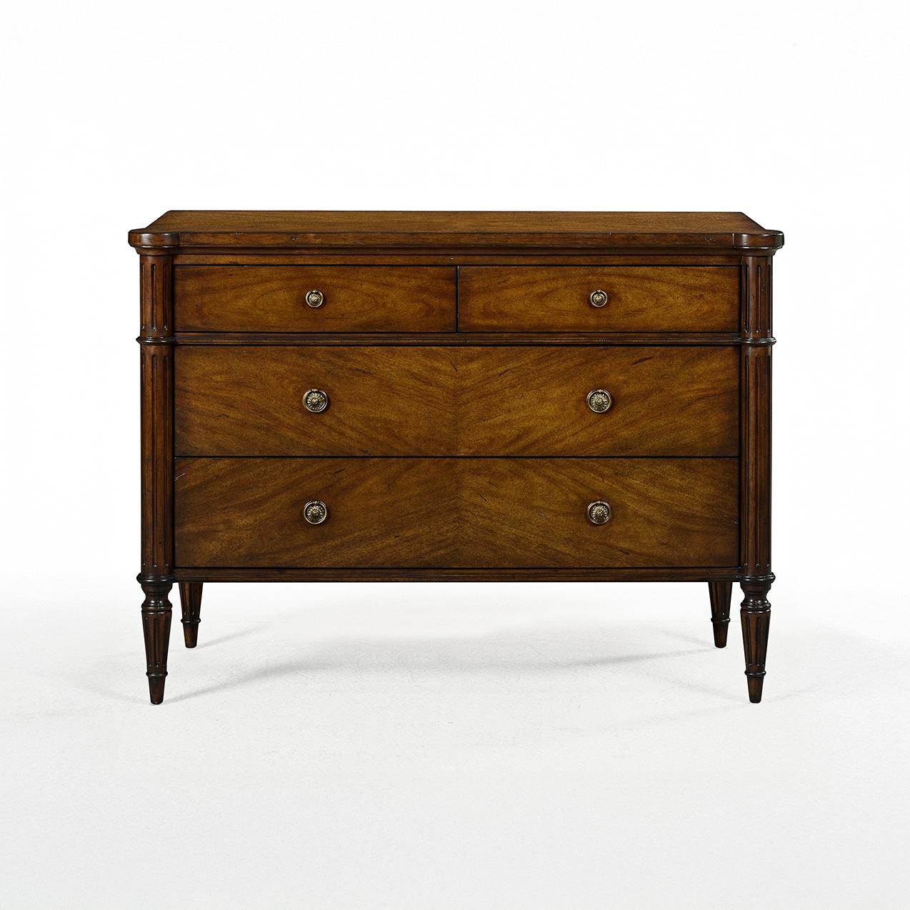 Realizzato nella tradizione del neoclassicismo francese del XVIII secolo, questo pezzo presenta una ricca finitura in mogano scuro su legno di acacia che mette in risalto le venature naturali e il calore del legno. Il comodino offre due cassetti