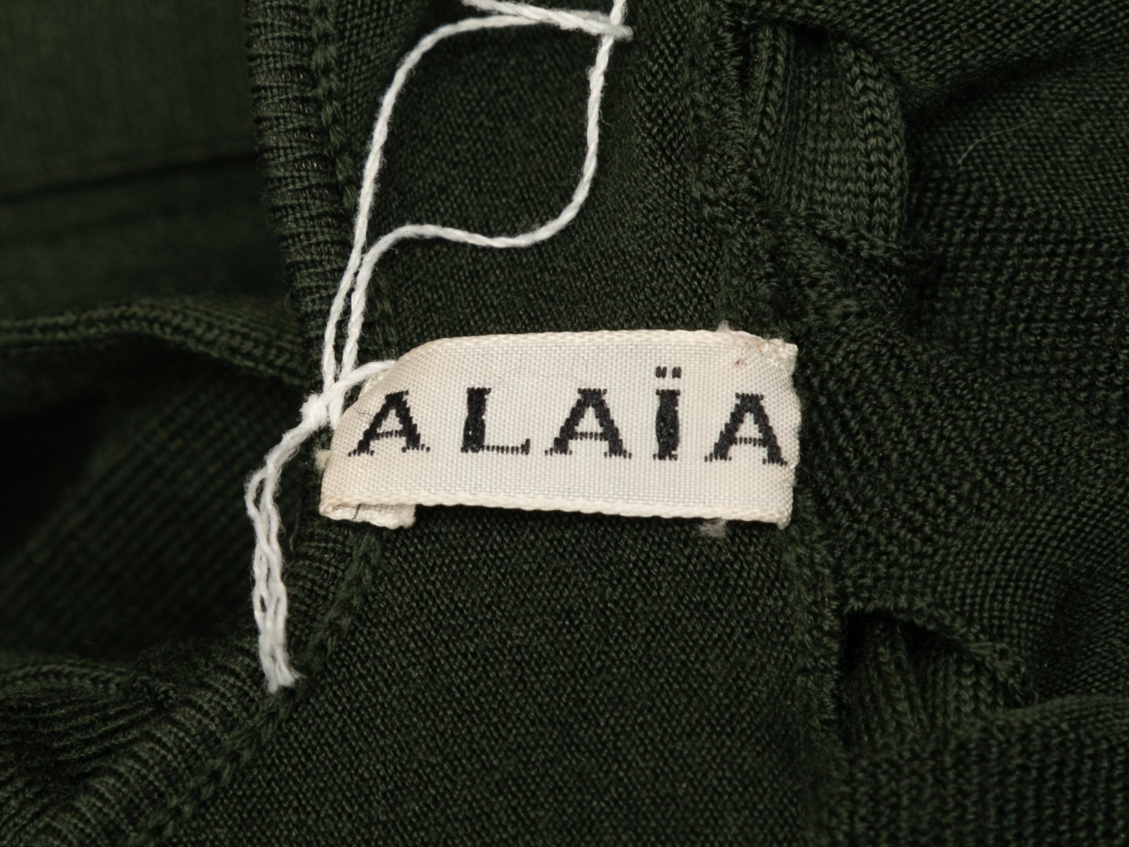 Dark green knit open back dress by Alaia. Crew neck. Short sleeves. Button closure at nape. 28