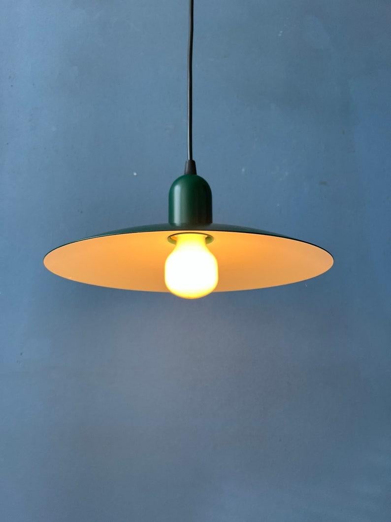 Un'esclusiva lampada a sospensione industriale vintage a forma di piattino di colore verde scuro realizzata in metallo. La lampada richiede una lampadina E27/26.

Informazioni aggiuntive:
Materiali: Metallo
Periodo: 1970s
Dimensioni: ø: 24