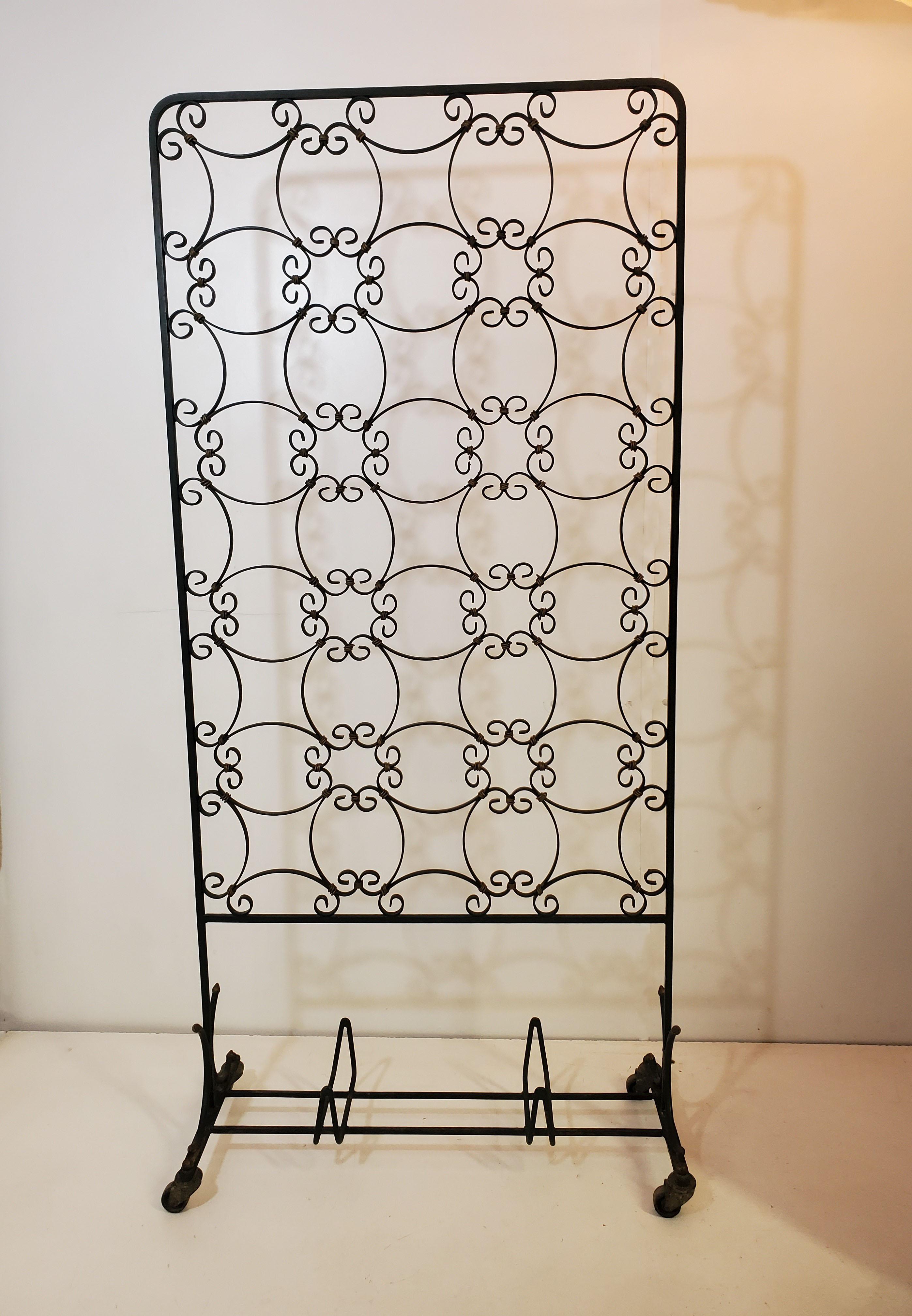 
A  unique and decorative French 1940's hand forged dark bottle green iron and hand coiled gilt iron room divider, rolling screen reflecting a blend of craftsmanship and artistic expression. The screen which can act as a decorative accent as well as