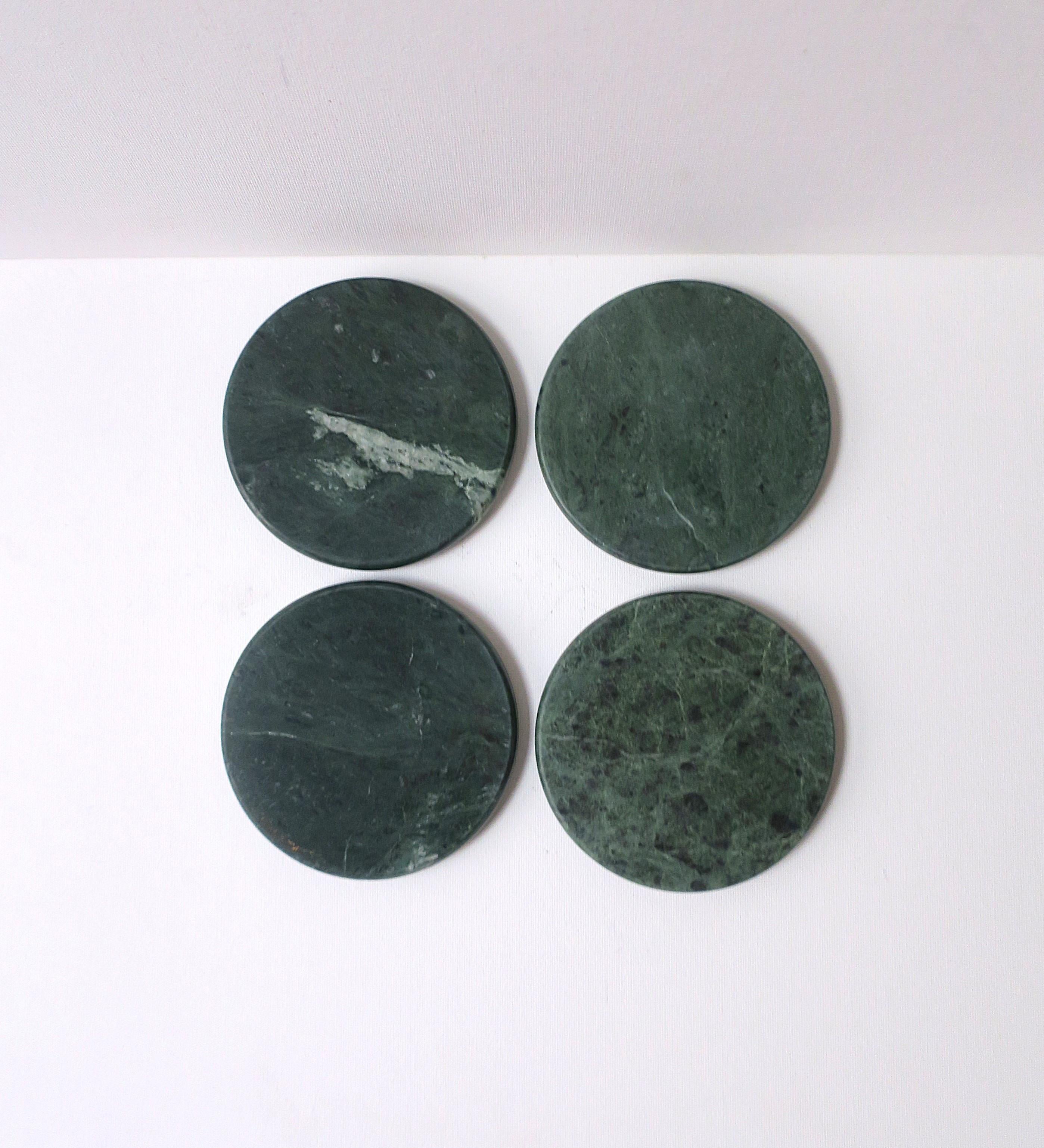 Un set di quattro (4) sottobicchieri rotondi in marmo verde scuro per bevande, cocktail, champagne, etc., stile moderno/periodo postmoderno, circa fine XX secolo. I sottobicchieri sono di colore verde scuro con tracce di venature bianche, con bordi