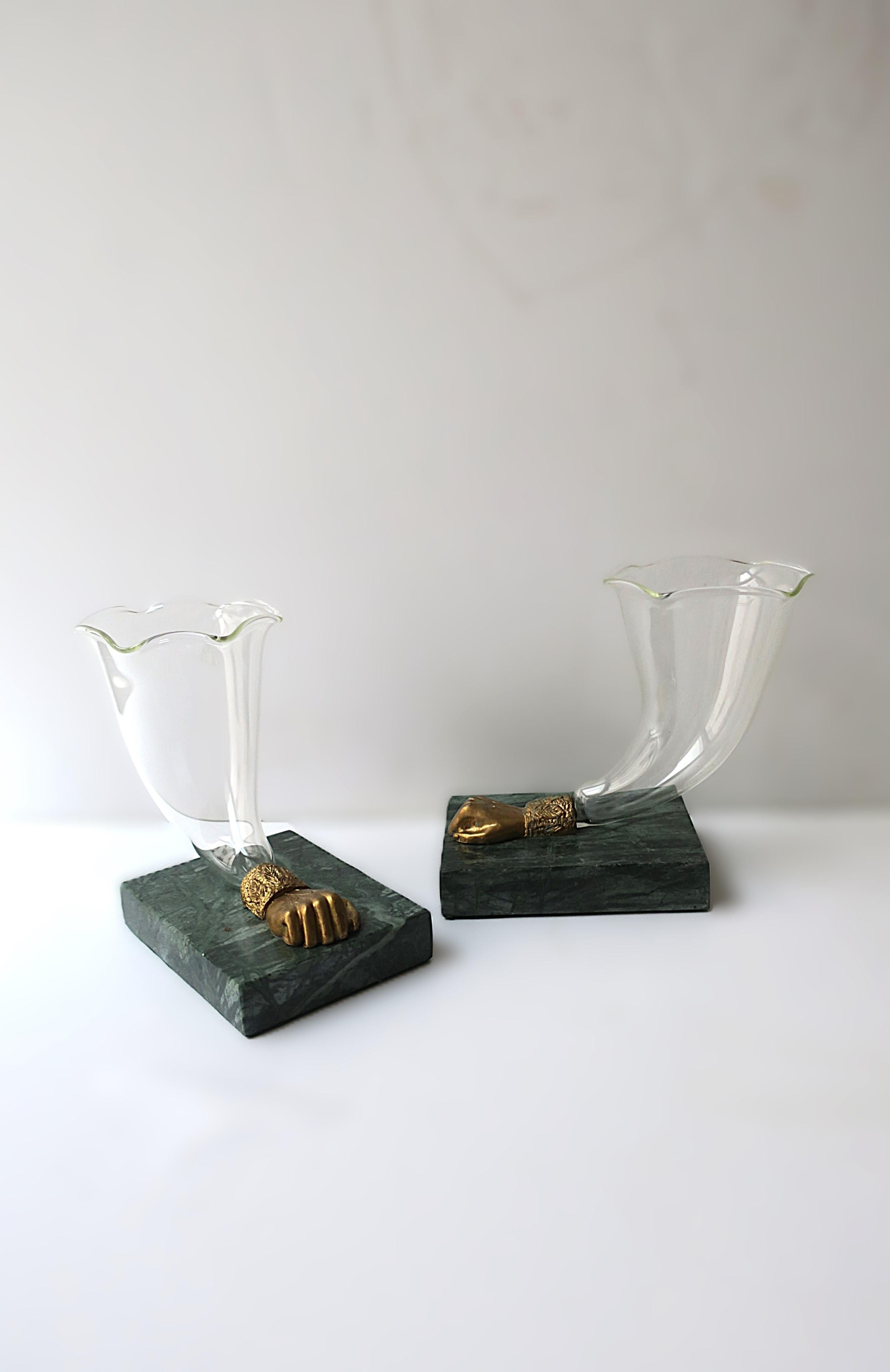 Una bella coppia di vasi scultura cornucopi inglesi a forma di tromba, circa 20° secolo, Inghilterra. Il set è in vetro soffiato trasparente con bordo smerlato, sostenuto da pugni in bronzo dorato su basi rettangolari in marmo verde scuro.
