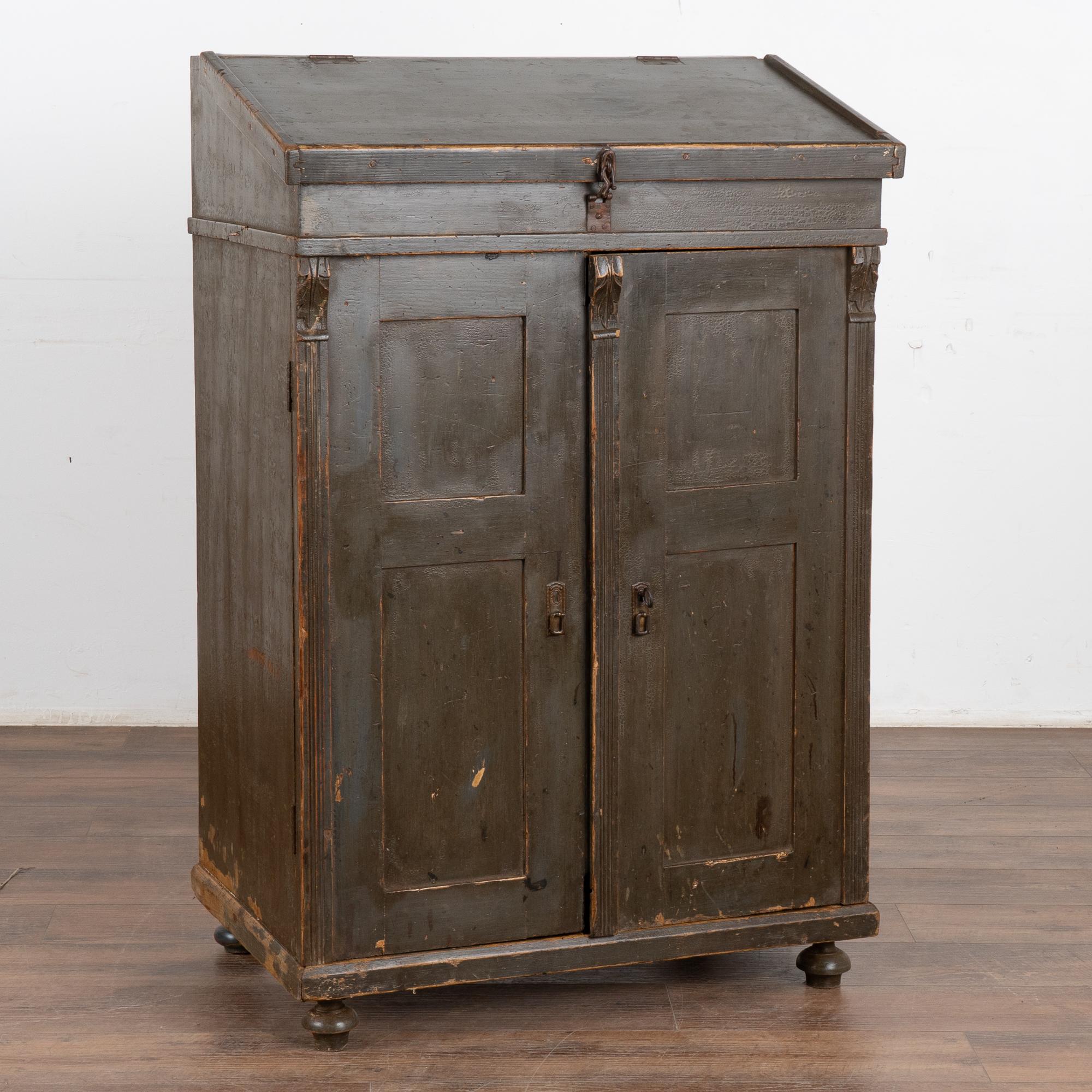 This original painted pine podium is an unusual find, with interior drawers/bins and desktop which opens to reveal storage as well.
The original green paint has a very dark hue, and reveals distress, scratches, marks, stains and crackles throughout