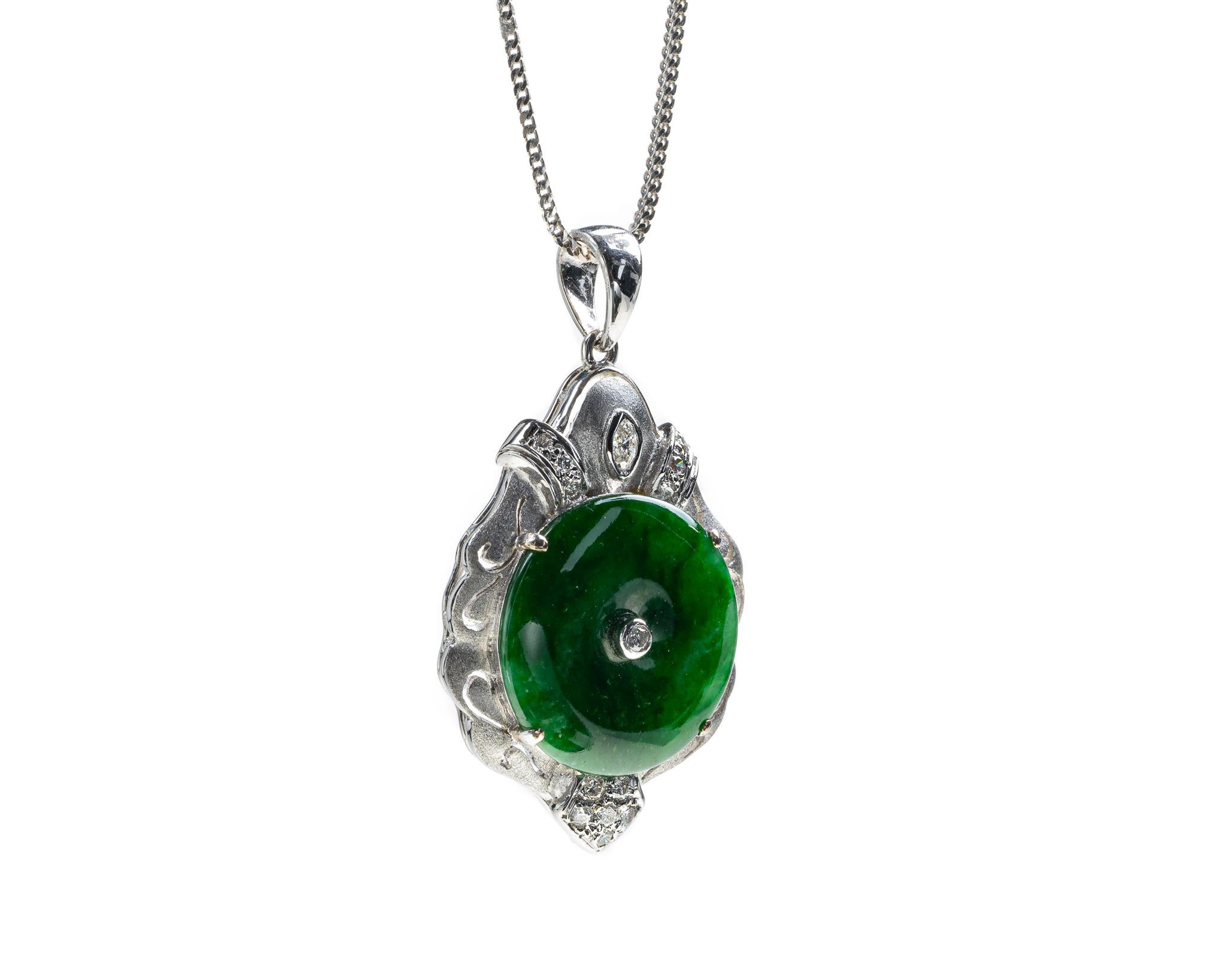 This is an all natural, untreated jadeite jade carved pi disc and diamond pendant set on an 18K white gold and diamond bail.  The carved pi disc symbolizes peace.   

It measures 1.24 inches (31.5mm ) x 0.83 inches (21.1 mm) with thickness of 0.21