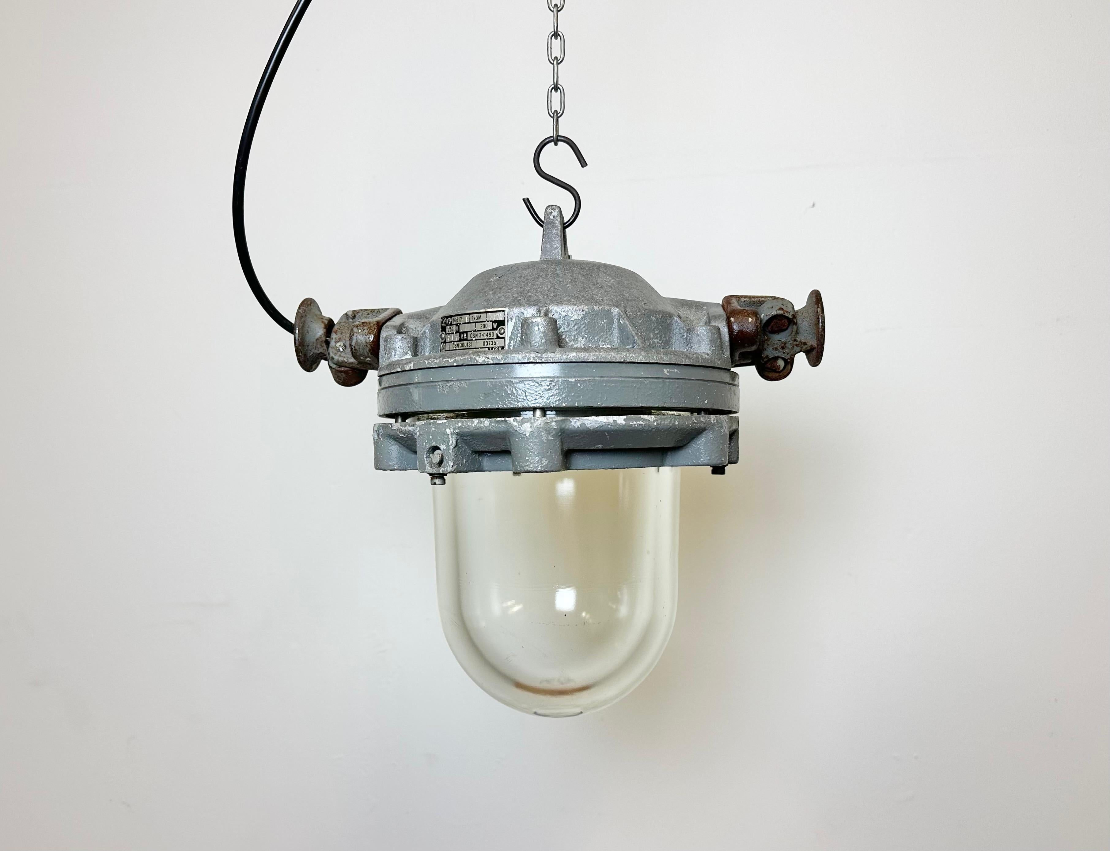 Dark grey industrial lamp with massive protective glass bulb made by Elektrosvit in former Czechoslovakia during the 1970s.It features a cast aluminium body and a explosion proof clear glass cover. Porcelain socket requires standard E27/ E26
