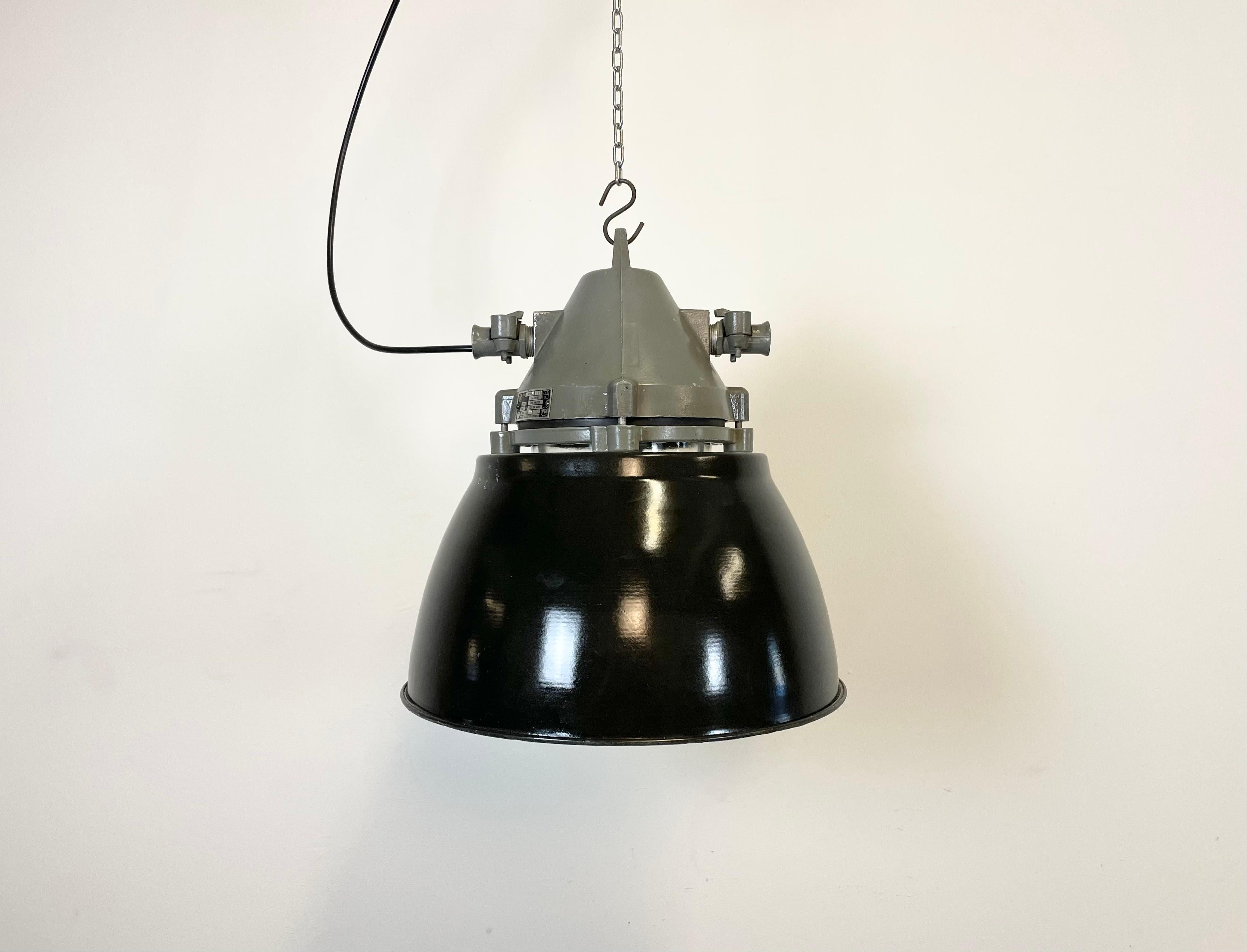 Dark grey industrial light with massive protective glass bulb. Cast aluminium body, clear glass. Black enameled shade with white interior. Porcelain socket for E27 light bulbs. Newly wired. Weight: 6.0 kg.