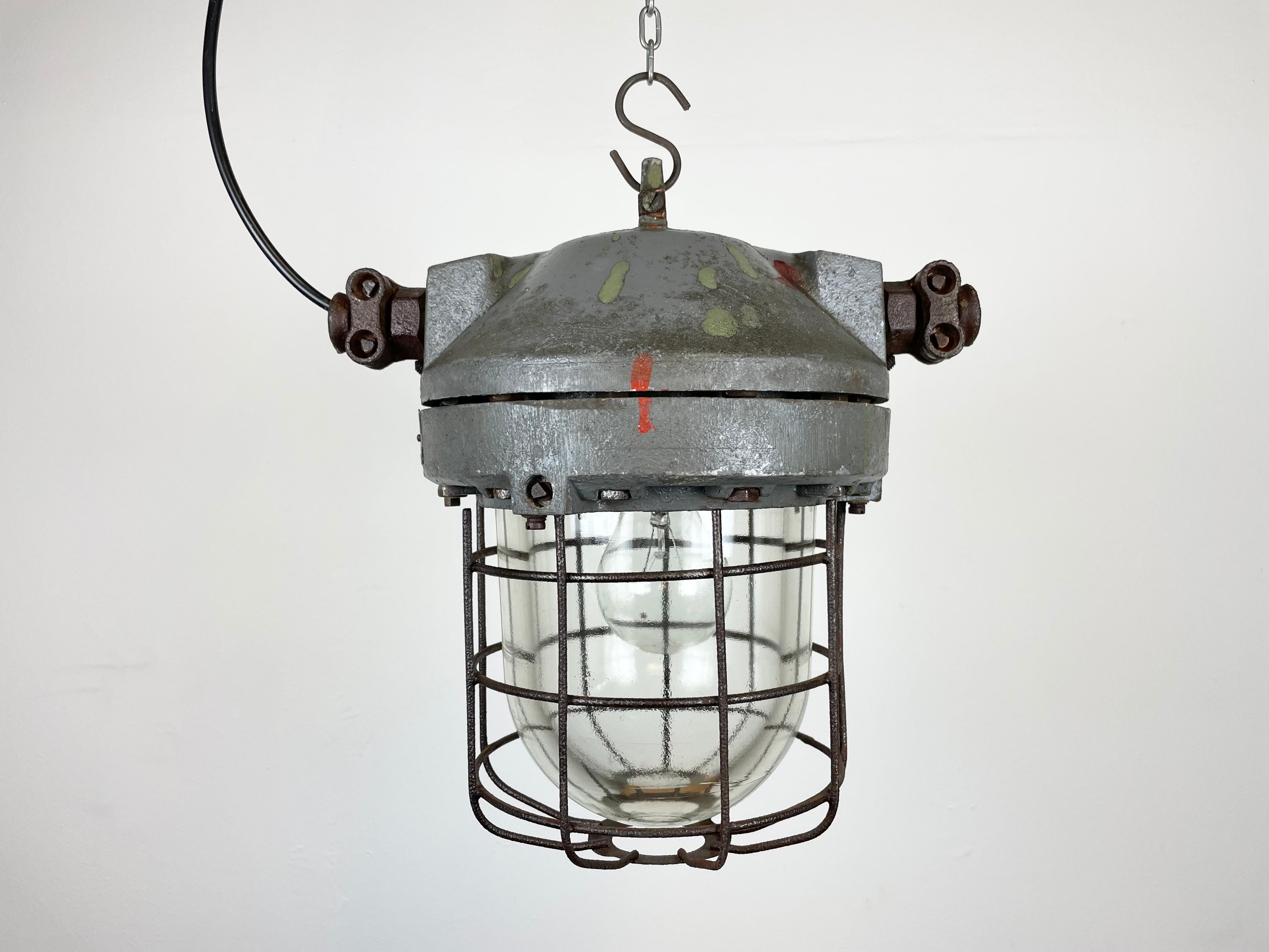 This industrial light was manufactured in former Czechoslovakia by Elektrosvit in the 1960s. It features a dark grey cast aluminum body, an iron cage and explosion-proof glass. The porcelain socket requires E 27 light bulbs.New wire. The weight of