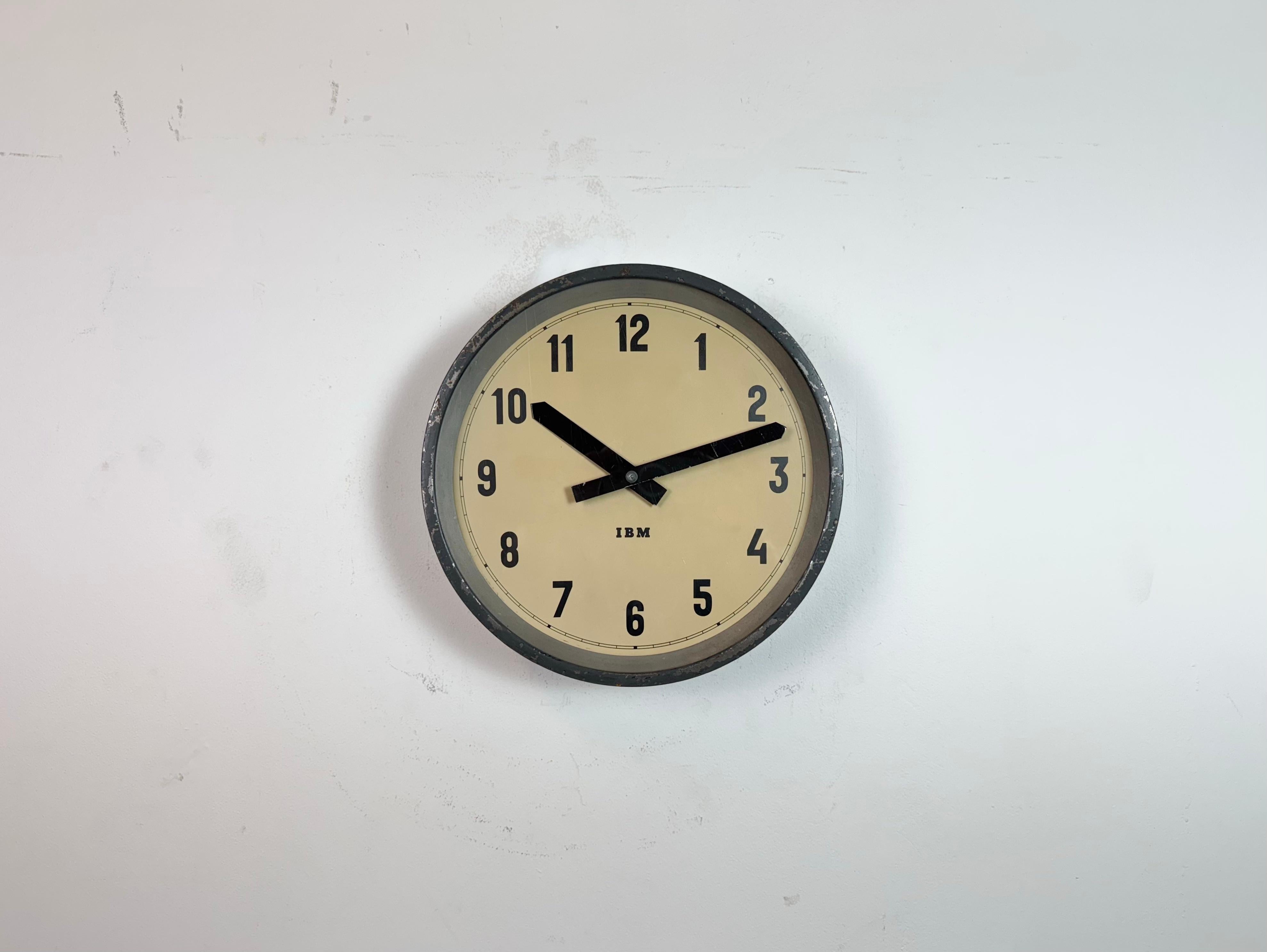 This wall clock was produced by IBM in USA during the 1950s. It features a dark grey metal frame, iron dial, aluminium hands and a clear glass cover. The piece has been converted into a battery-powered clockwork and requires only one AA-battery. The