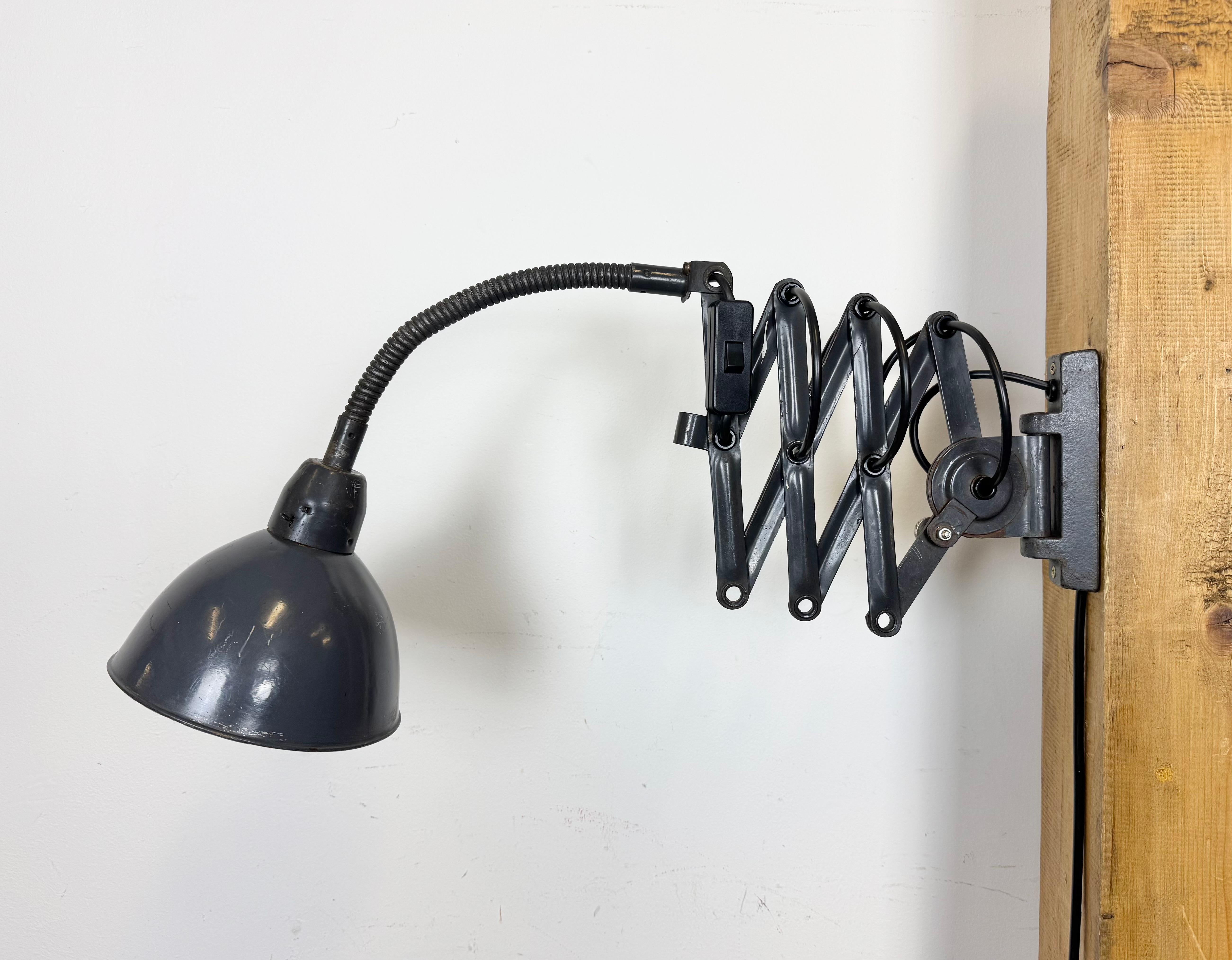 This vintage industrial adjustable gooseneck grey scissor wall light was produced by Elektroinstala Dečín in former Czechoslovakia during the 1960s. It has a metal lampshade. The iron scissor arm is extendable and can be turned sideways. The socket