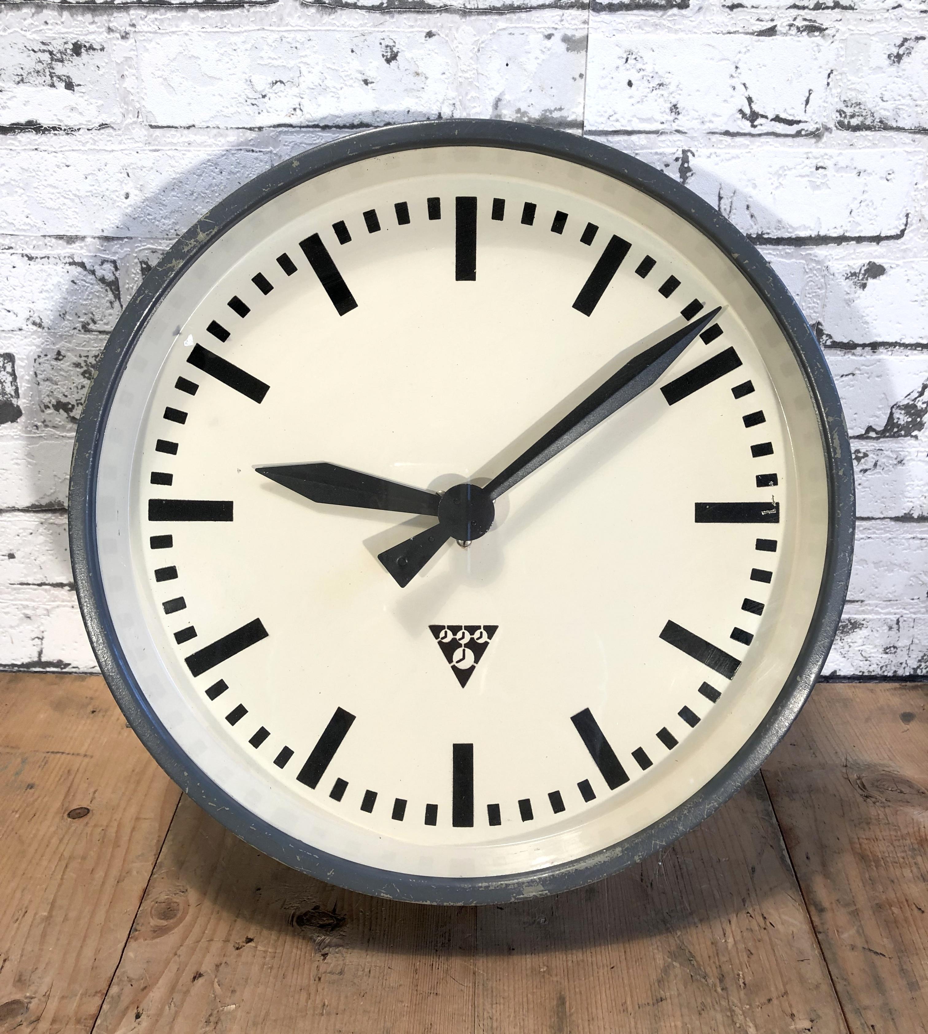 These Pragotron wall clock was made in former Czechoslovakia during the 1960s. It Features a dark grey metal frame, iron dial and clear glass cover. The piece has been converted into a battery-powered clockwork and requires only one AA-battery.