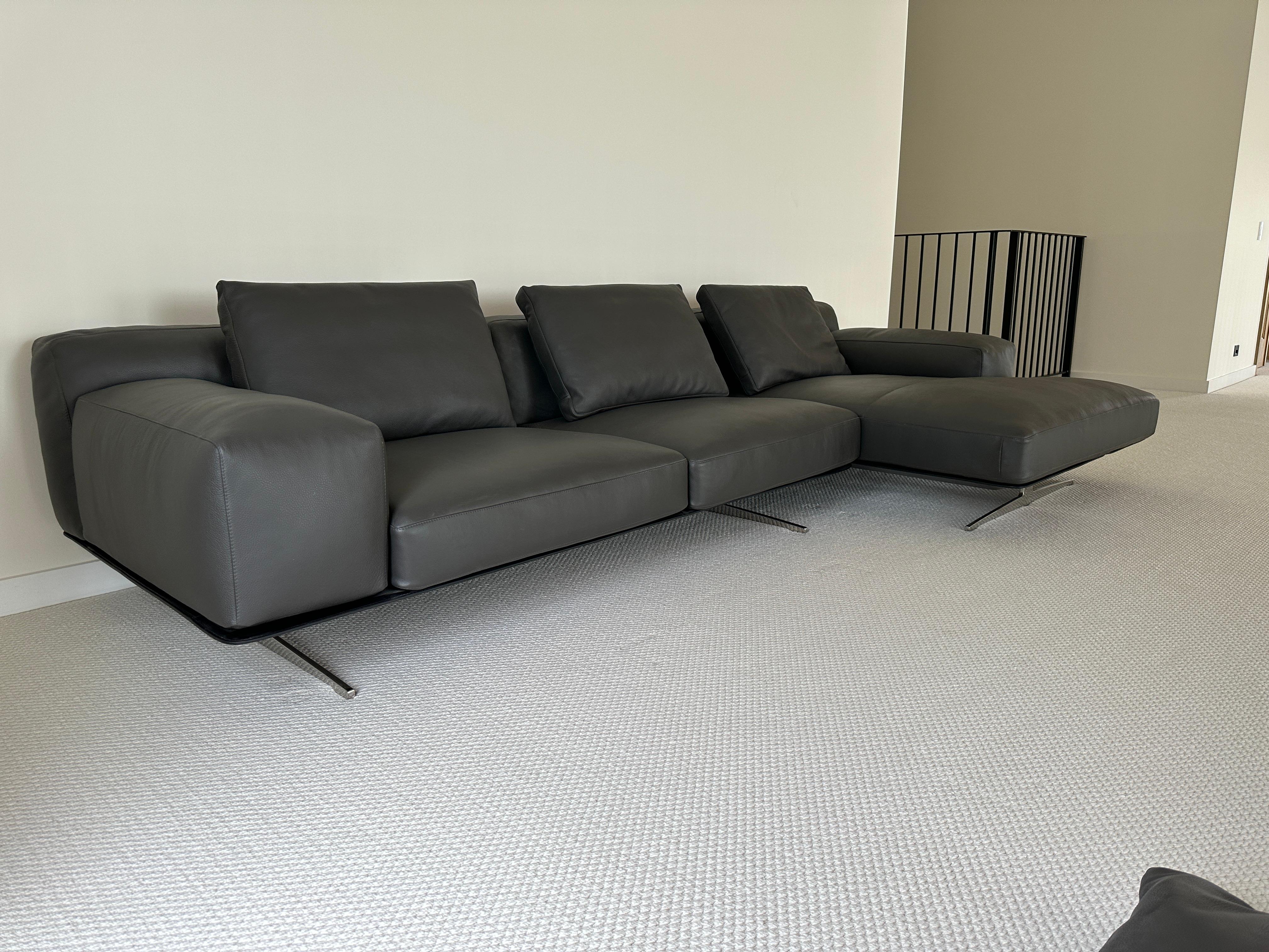 Essentially unused dark grey leather sectional, hand made in Lake Como, Italy and purchased through Palazzetti. Features low profile, wide armrests, thick solid seat and backrest cushions with sleek and minimal chrome legs. Comes with three backrest