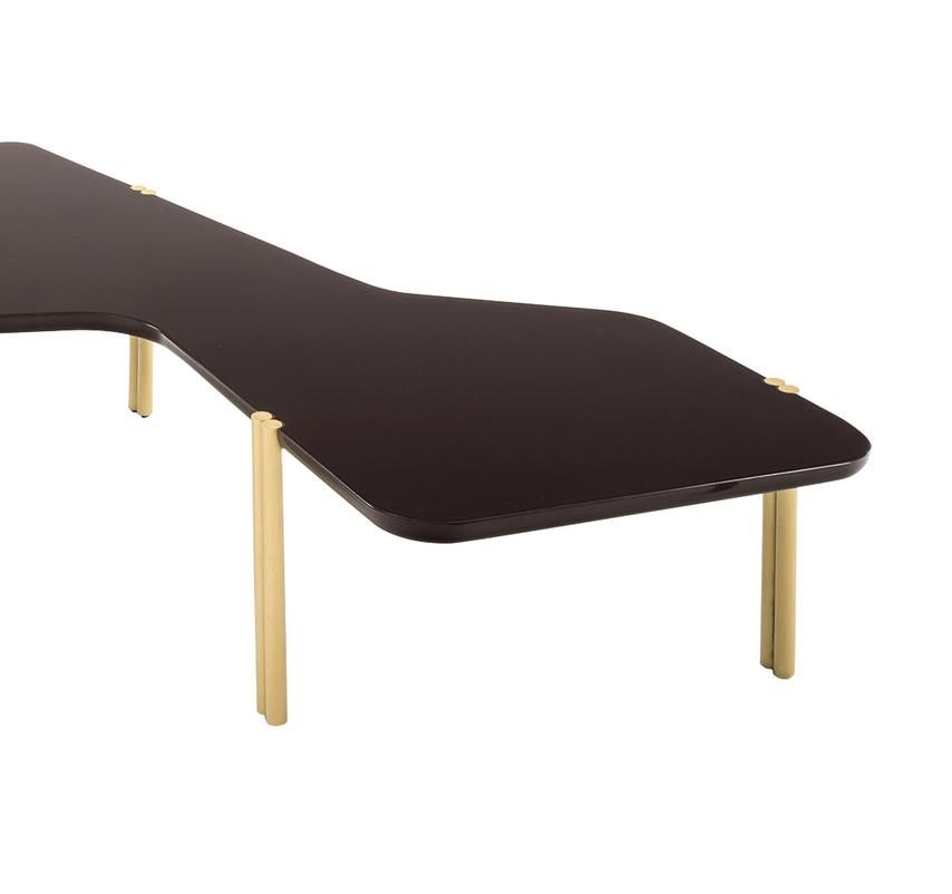 Part of the Jean collection of asymmetrical and stackable tables that pay tribute to Hans Arp's abstract art, this coffee table has a dynamic silhouette enhanced by irregular lines with slight bends and five double legs made of brass cylinders with
