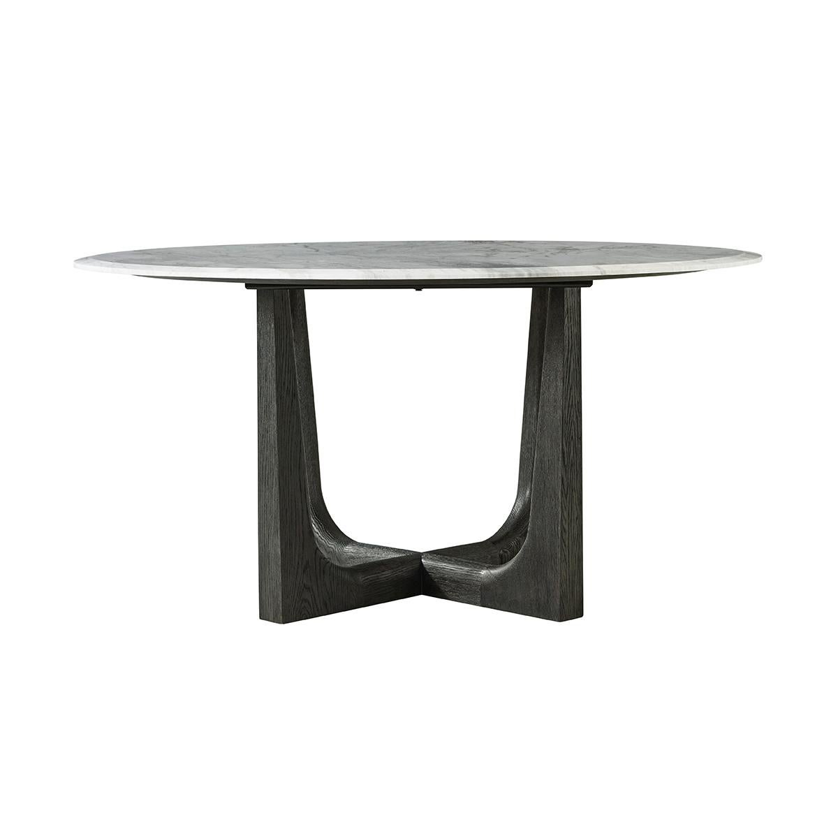 A round marble top dining table that seats six comfortably. Its X-form base and elegant legs in our dark charcoal oak finish reach upwards to perfectly balance the stone giving the impression of lightness. The beveled edge of the marble adds comfort