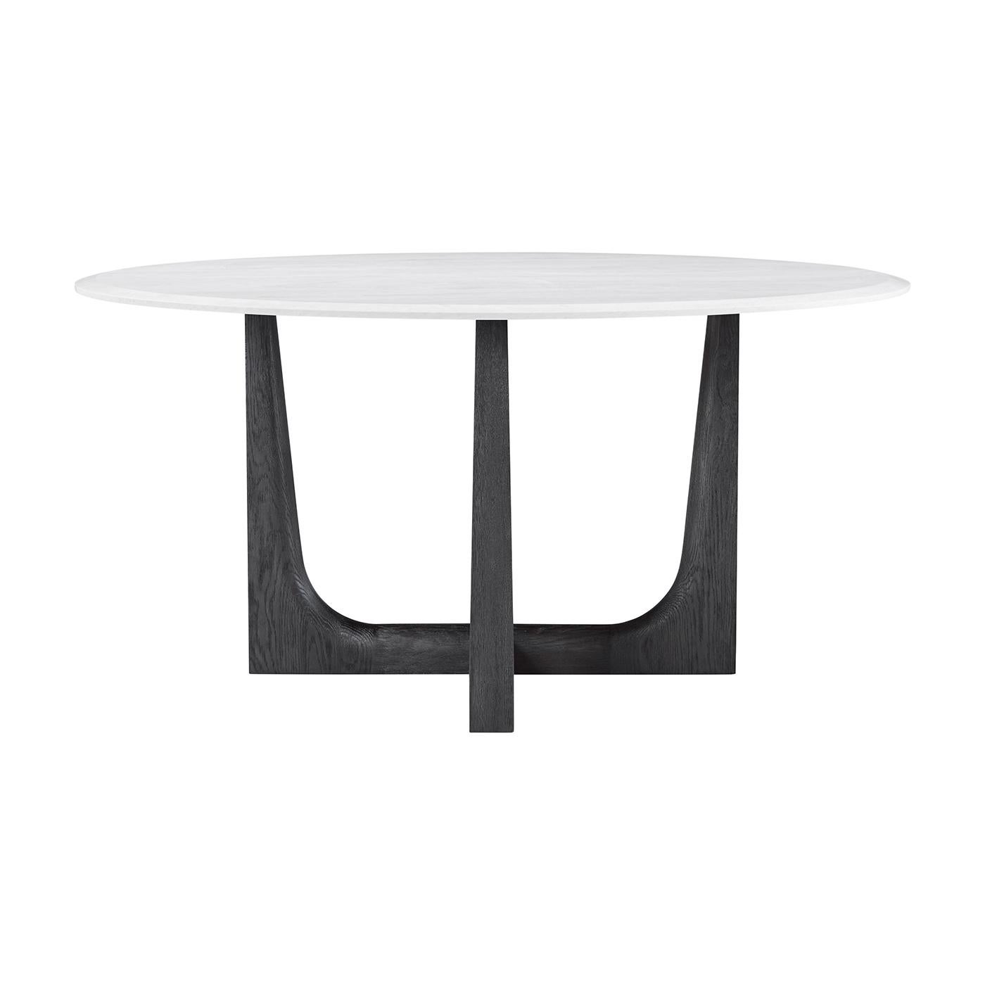 Una mesa de comedor redonda con tablero de cuarzo en la que caben seis personas cómodamente. Su base en forma de X y sus elegantes patas en nuestro acabado de roble carbón oscuro se extienden hacia arriba para equilibrar perfectamente la piedra,