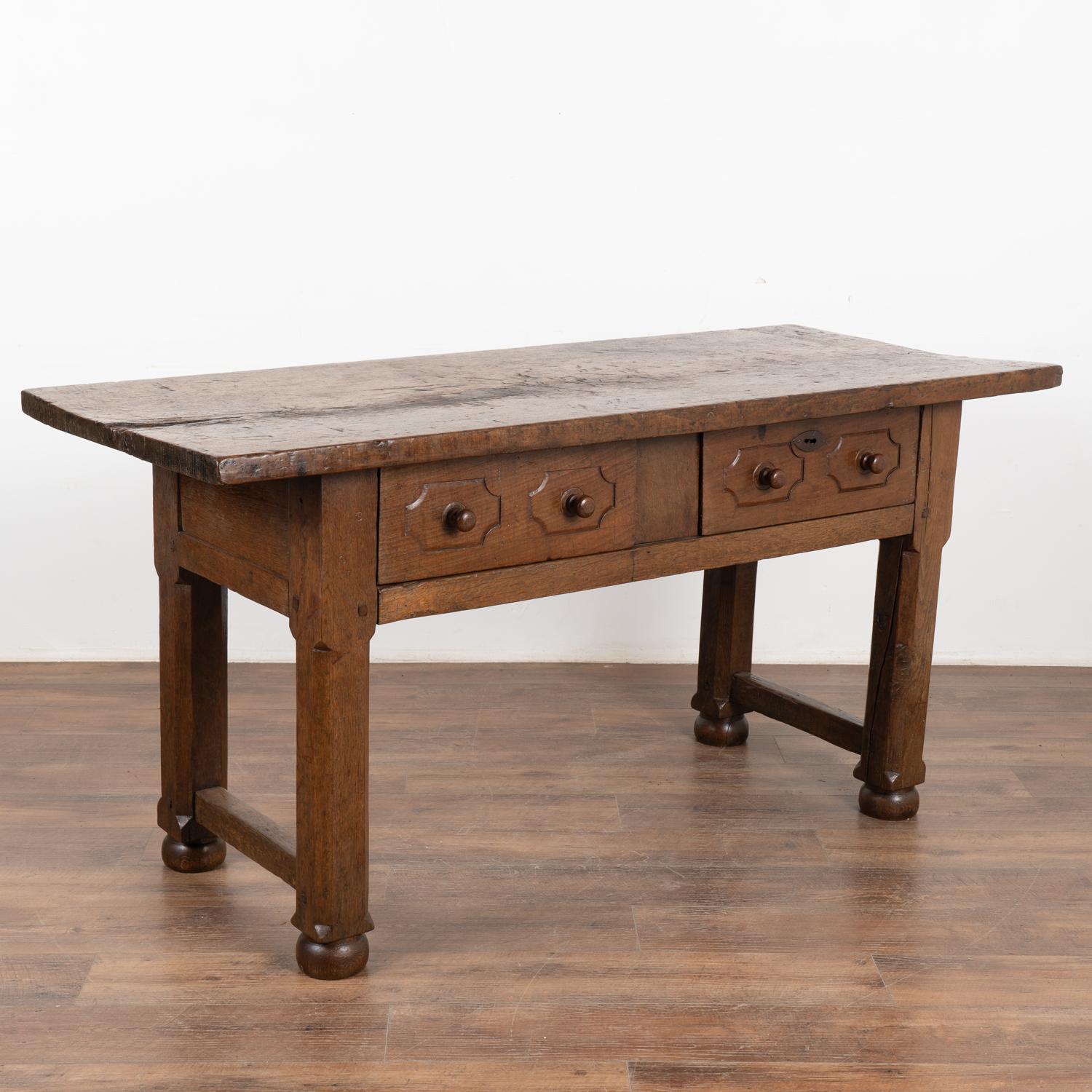 Dark oak console table with two drawers from Spain.
Please enlarge photos (especially of top) to appreciate the dark patina of the wood, including old cracks, gouges, stains and nicks that add to the aged appeal of this handsome table.
At 5.5' long,