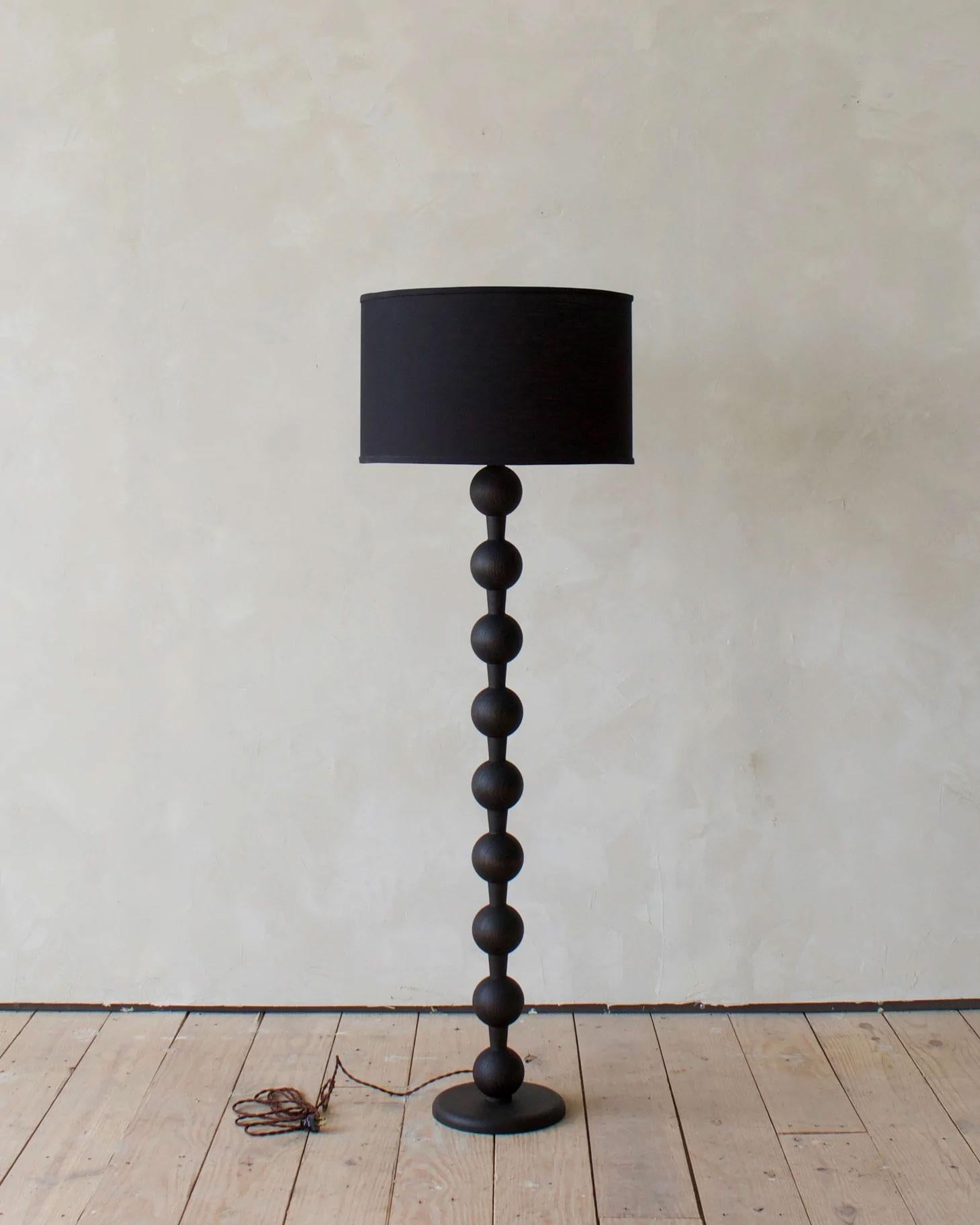 The charming sculptural design of the Hugo Barbell floor lamp is certain to add character to any room. Hand-crafted in Pennsylvania, the solid oak balls create a fixture that is as sturdy as it is stylish. The grained oak texture shows through the