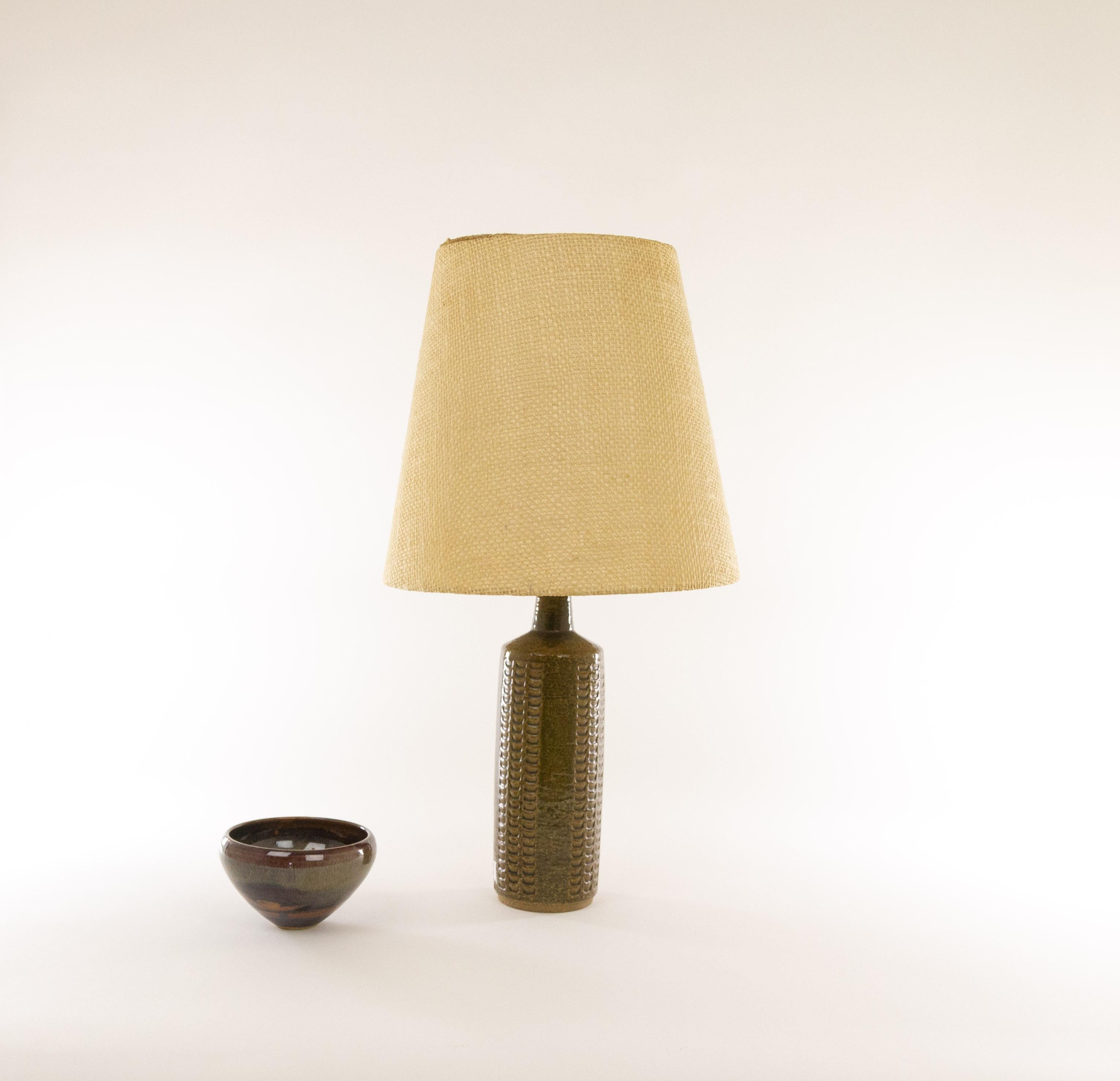 Une lampe de table DL/27 réalisée par Annelise et Per Linnemann-Schmidt pour Palshus dans les années 1960. La couleur de cette pièce est Olive foncé avec des traces d'Ambre.

La lampe est livrée avec son support d'abat-jour d'origine. L'abat-jour