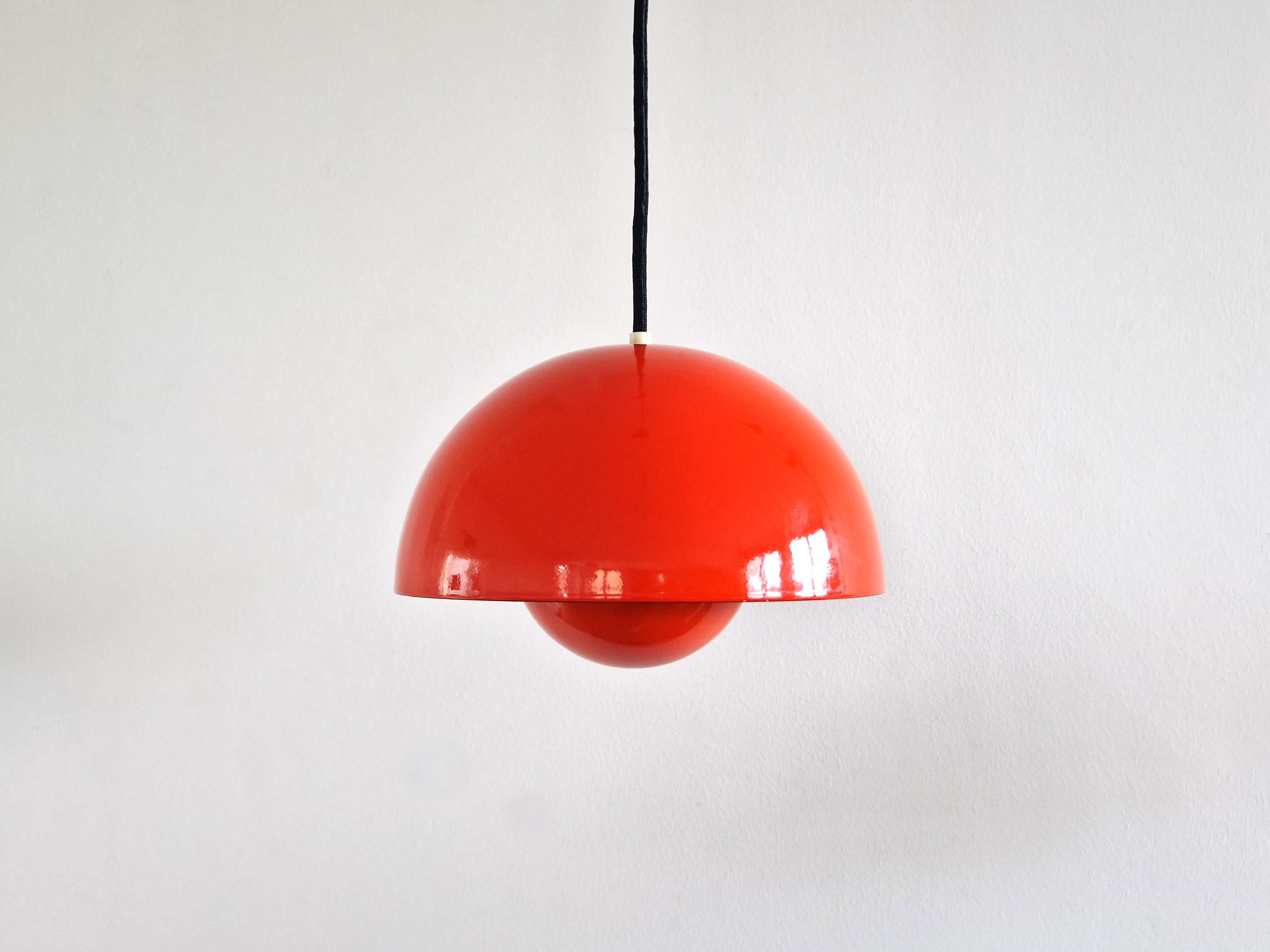 The Flowerpot pendant lamp was designed by Verner Panton for Louis Poulsen in 1968. A beautiful design classic that is still in production. This lamp is an early version and has a dark orange enameled finish outside and white inside. The smaller