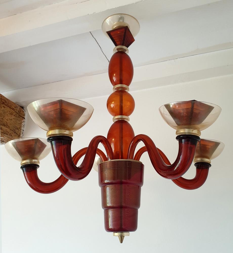 Dark orange Murano glass Mid-Century chandelier, attributed to Mazzega, Italy 1970s.
The mid-century modern chandelier has a dark orange, or dark caramel beautiful warm color, and gold flakes elements.
The vintage chandelier has 5 arms/lights.
It is