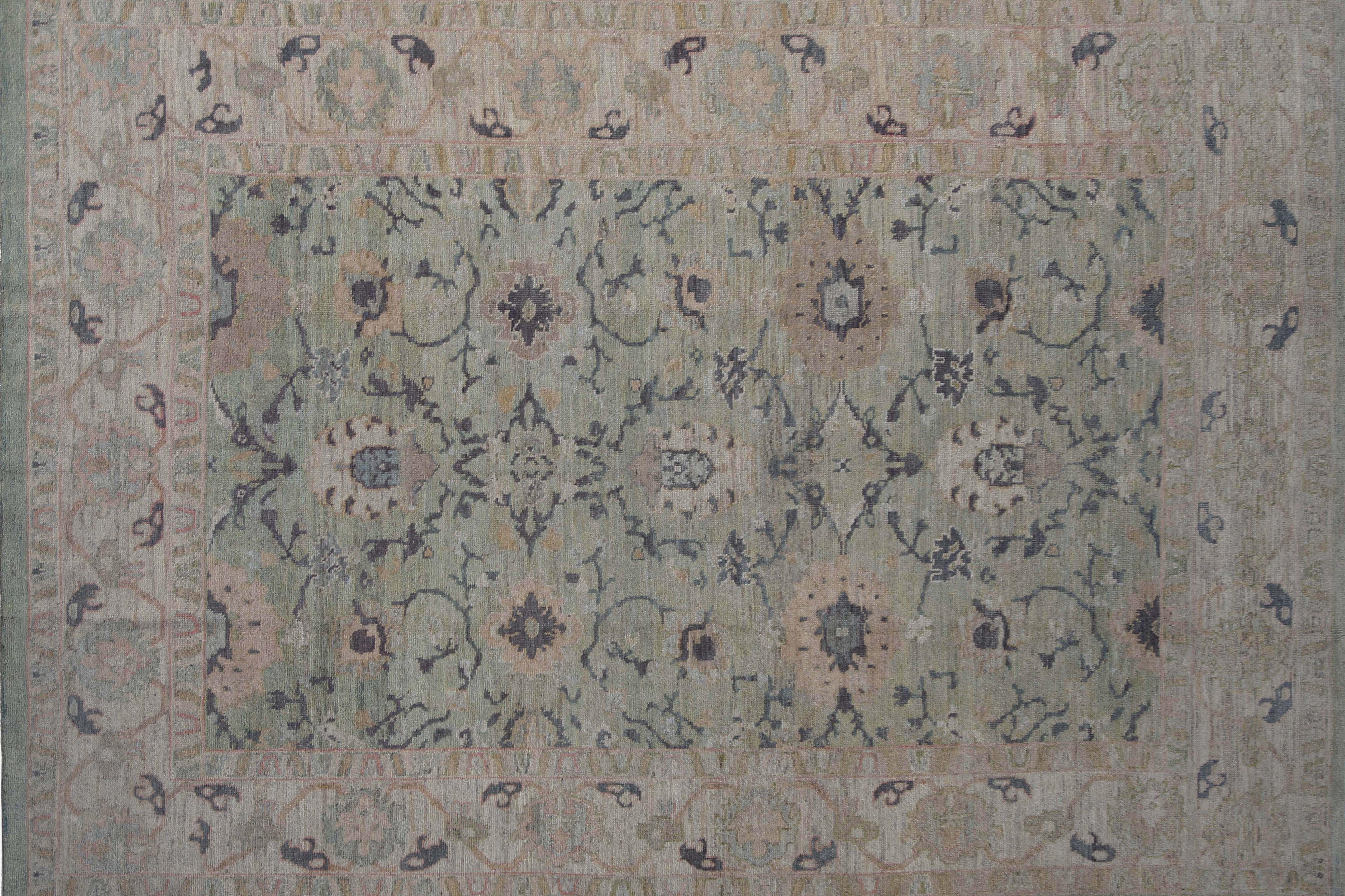 Il s'agit d'une description de produit pour un tapis turc Oushak qui mesure 9'6'' par 13'4''. Le tapis a un fond clair avec des touches de couleurs sombres telles que le bleu, le blush et le vert. Il présente un design traditionnel à la fois élégant