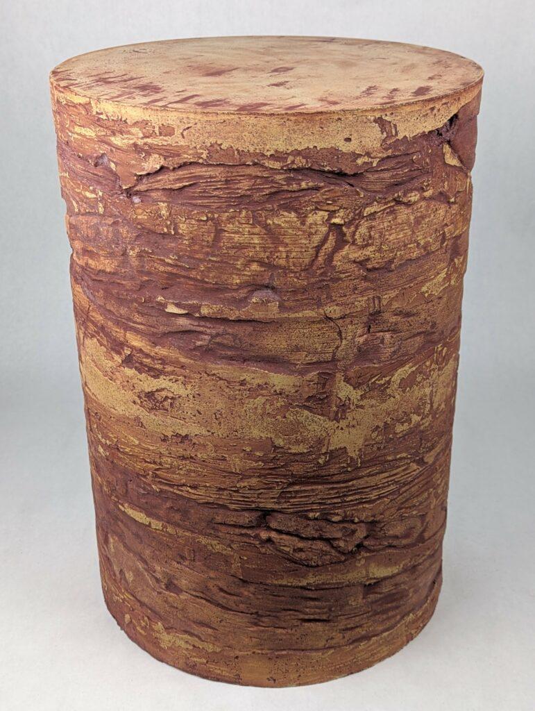 Unusual textured concrete side table or stool with dark purple colored, swirling patterns from palm tree bark. It demands to be a resting point on in the shade of an oak tree on a hot dusty trail in a vineyard, but it would be just as happy in a