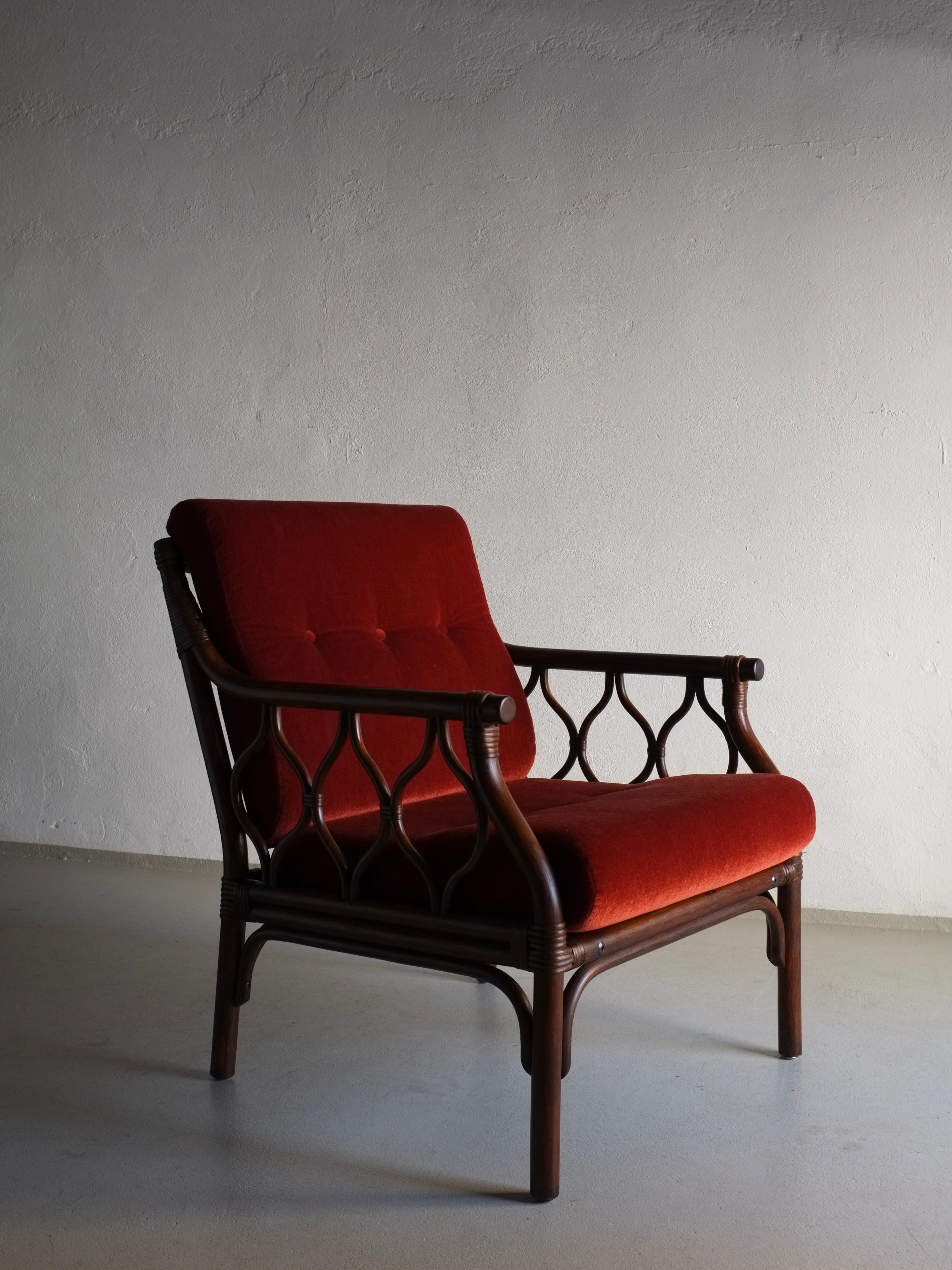 Dark rattan easy chair with vermilion red-orange velour cautions. A 2-seater sofa, a 3-seater sofa, and a coffee table from this set are available.

H(total/frame) 84/77 cm, h(seat) 44 cm, W 65 cm, D 75 cm