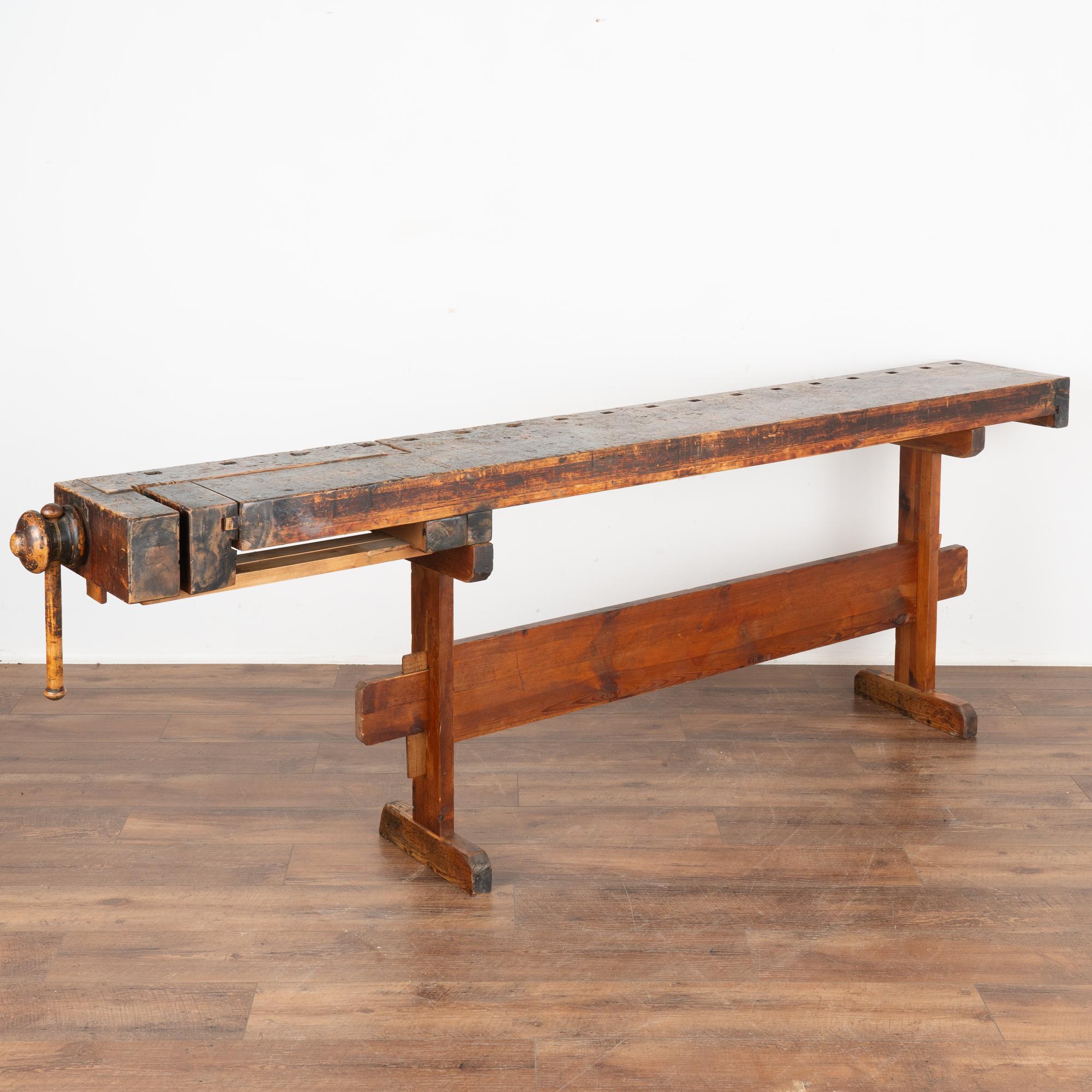 The dark patina of this old carpenter's workbench is a reflection of its age and years of use. Every ding, scratch, deep gouge, paint spill and stain enrich its character and appeal of this rustic console, just over 8' long.
This work table is