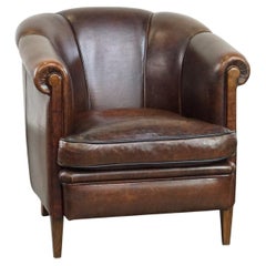 Dark sheep leather club chair with uniquely shaped armrests