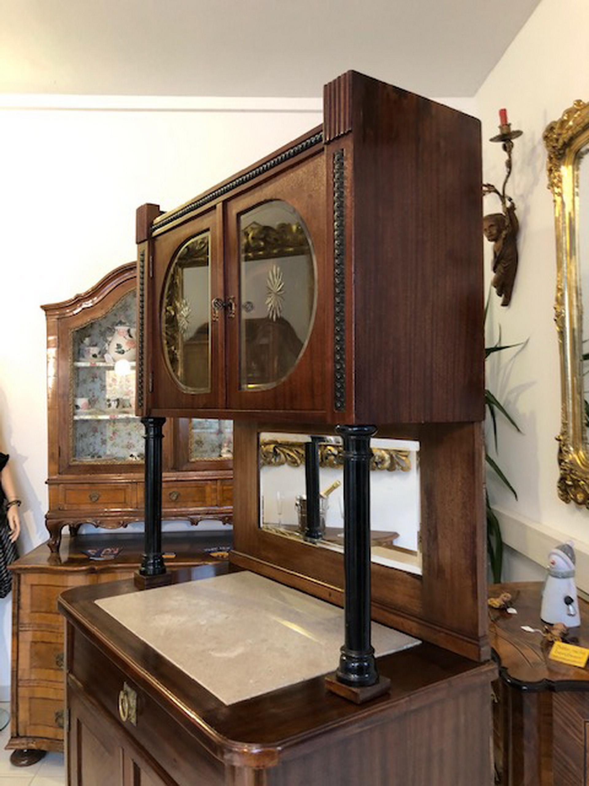 Narrow walnut wood buffet or small cabinet with a beautiful symmetric veneer picture. Offers typical Art Deco design with framing black columns and storage space behind four doors and one drawer. In the middle you can find a new cut mirror, while