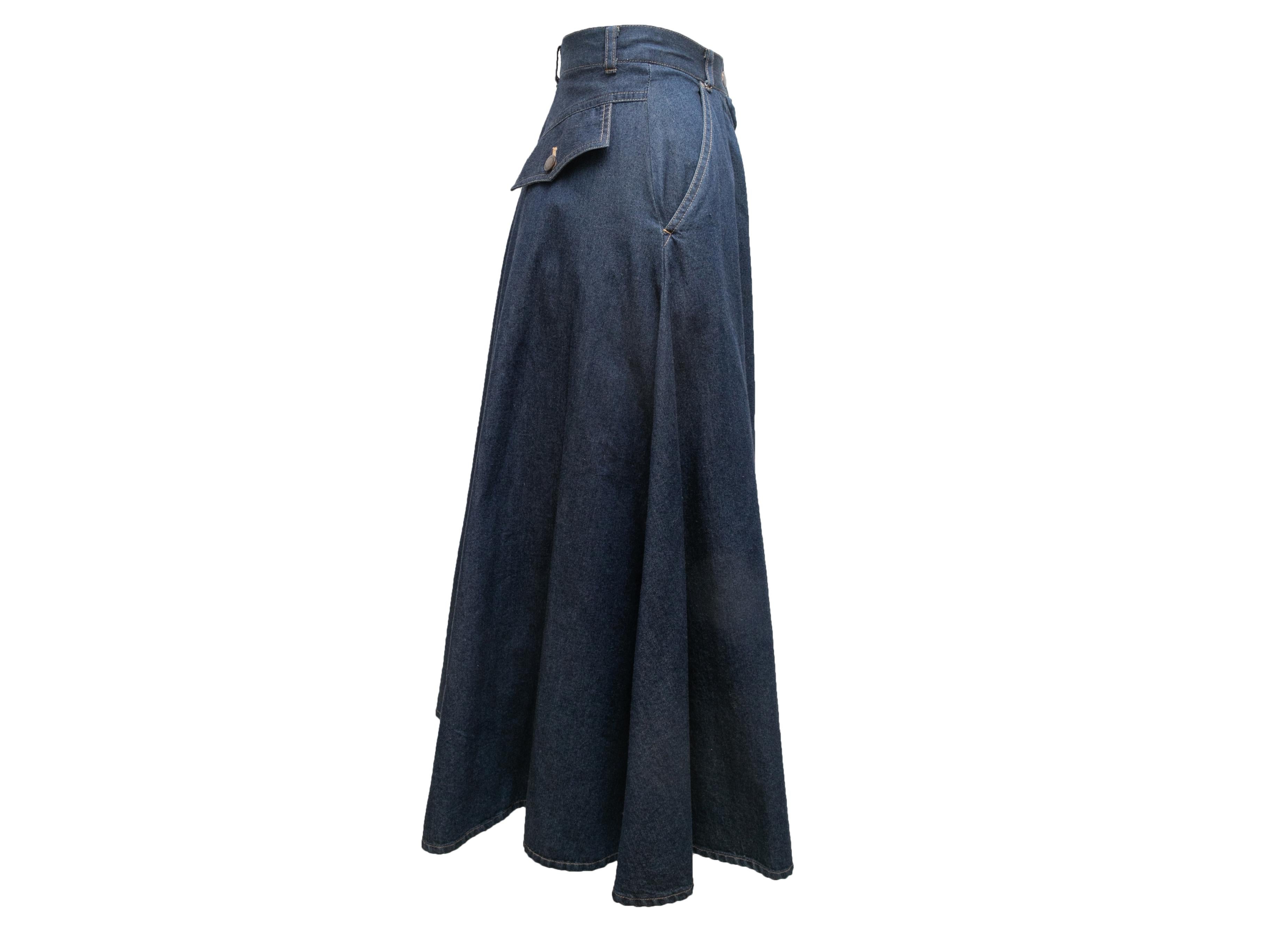 Dark wash denim swing skirt by Norma Kamali. Contrast stitching throughout. Four pockets. Zip and button closures at front. 24