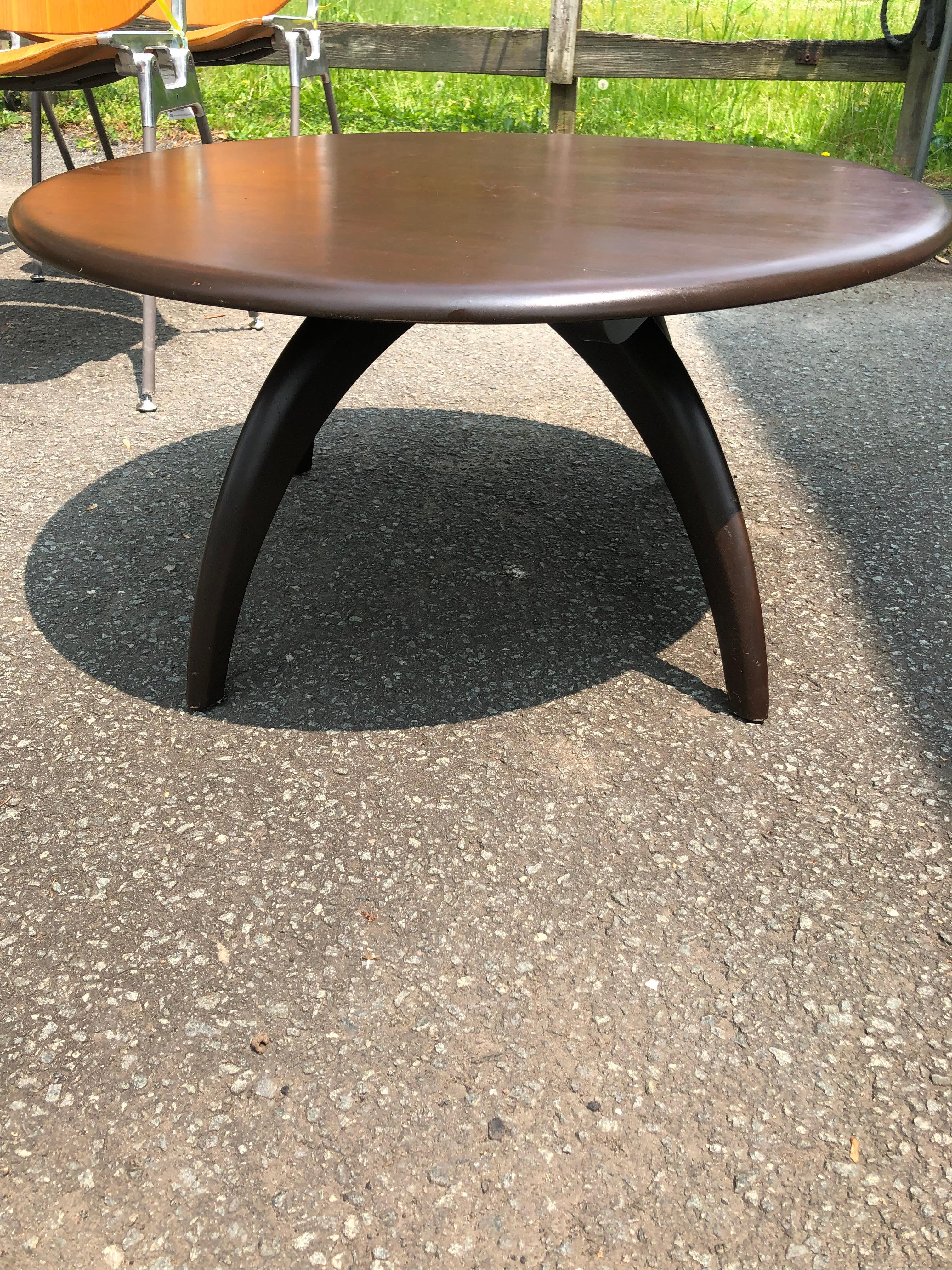 A handsome round dark oak small coffee table by Heywood Wakefield having 4 splayed legs and a top that swivels.